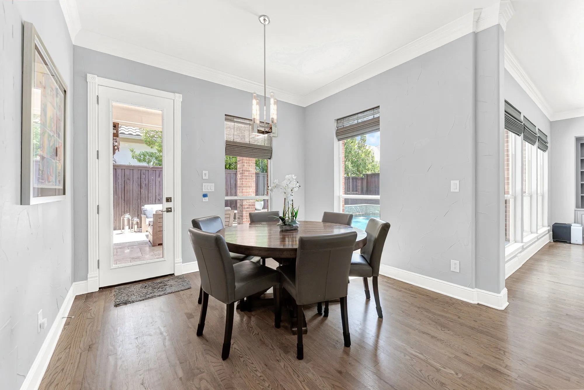 Framed by warm hardwood floors, this sunlit breakfast nook offers direct patio access and incredible views of the outdoor pool. Enjoy peaceful morning coffee while gazing out at the serene backyard water features.