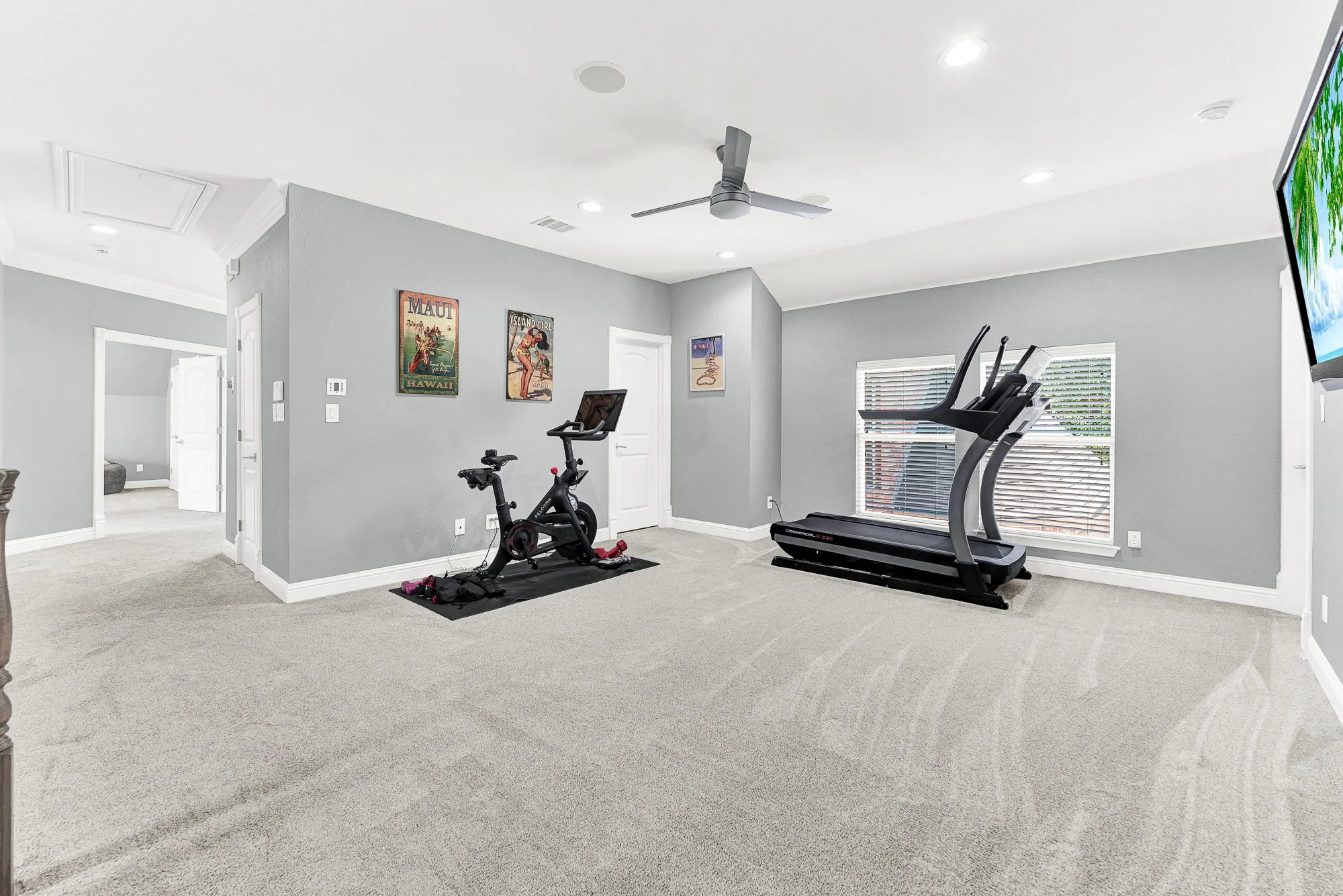 This expansive game room features plush neutral carpeting, a modern ceiling fan, recessed lighting, and bright natural light from the double windows. Customize this versatile space into a dedicated fitness area, hangout zone, or play area to perfectly suit your family's daily lifestyle.