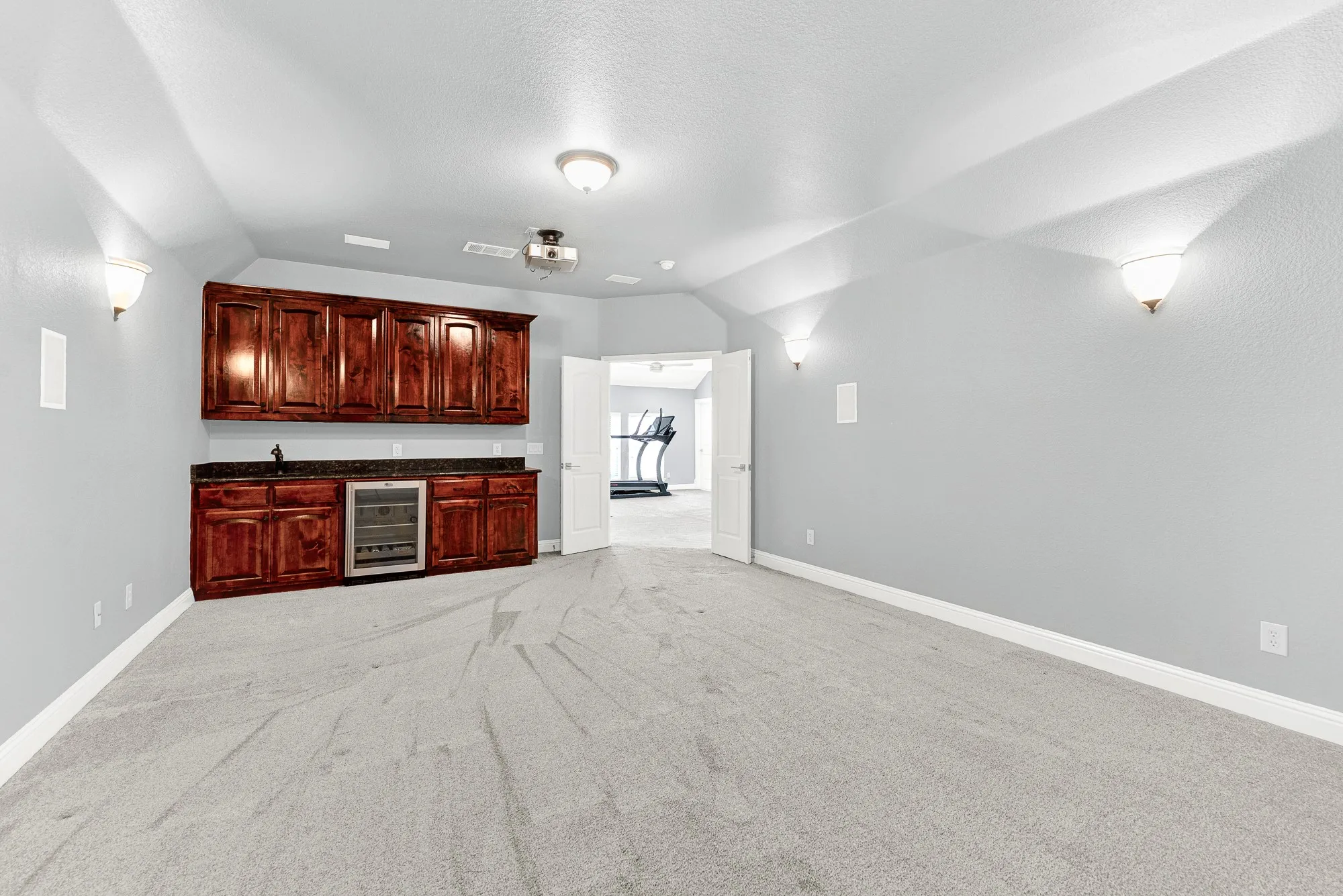 Rich wood cabinetry anchors a full wet bar with a built-in beverage fridge along the back wall. Grab chilled drinks and movie snacks without ever having to leave the entertainment action upstairs.