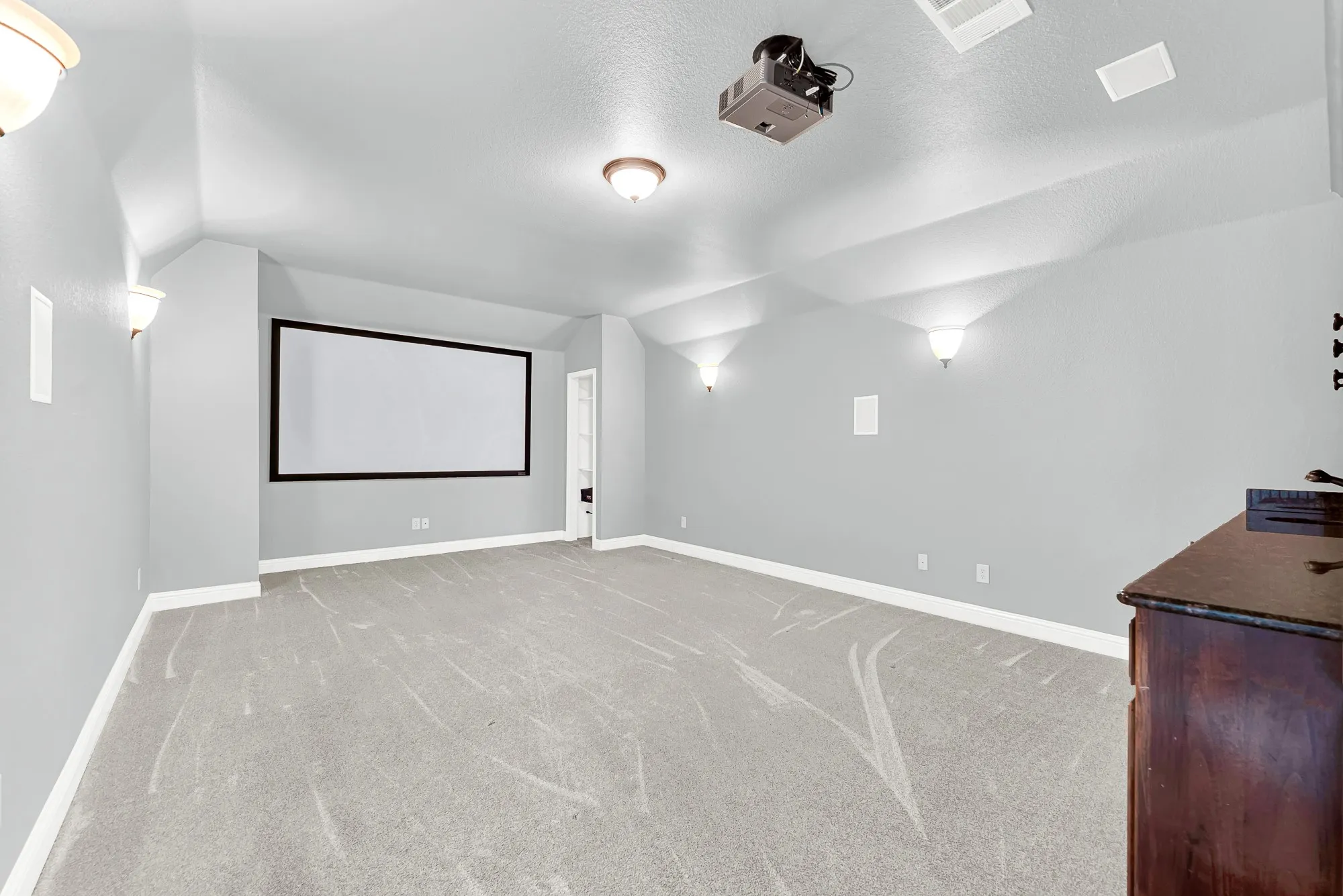 A large projection screen, ambient wall sconces, and soft plush carpeting set the stage in this dedicated media room. Host unforgettable movie nights or watch the big game with family in total comfort and theater-style style.