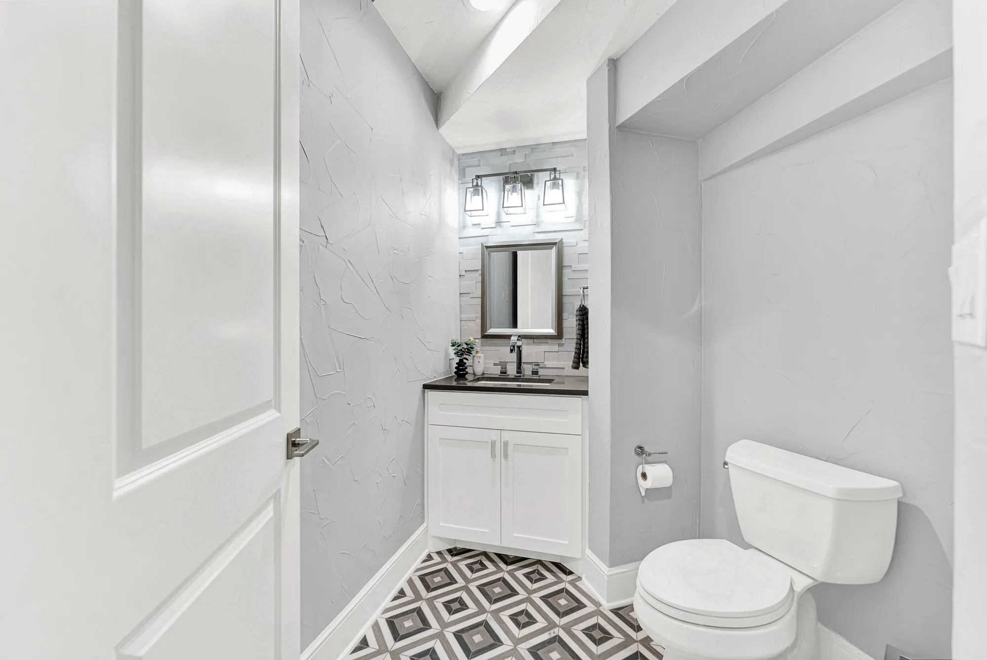 Renovated in 2019, this stylish half bath features custom vanity cabinetry, a dark quartz counter, modern lighting, and patterned floor tile. Guests will love stepping into this thoughtfully designed, fresh space during dinner parties and social visits.