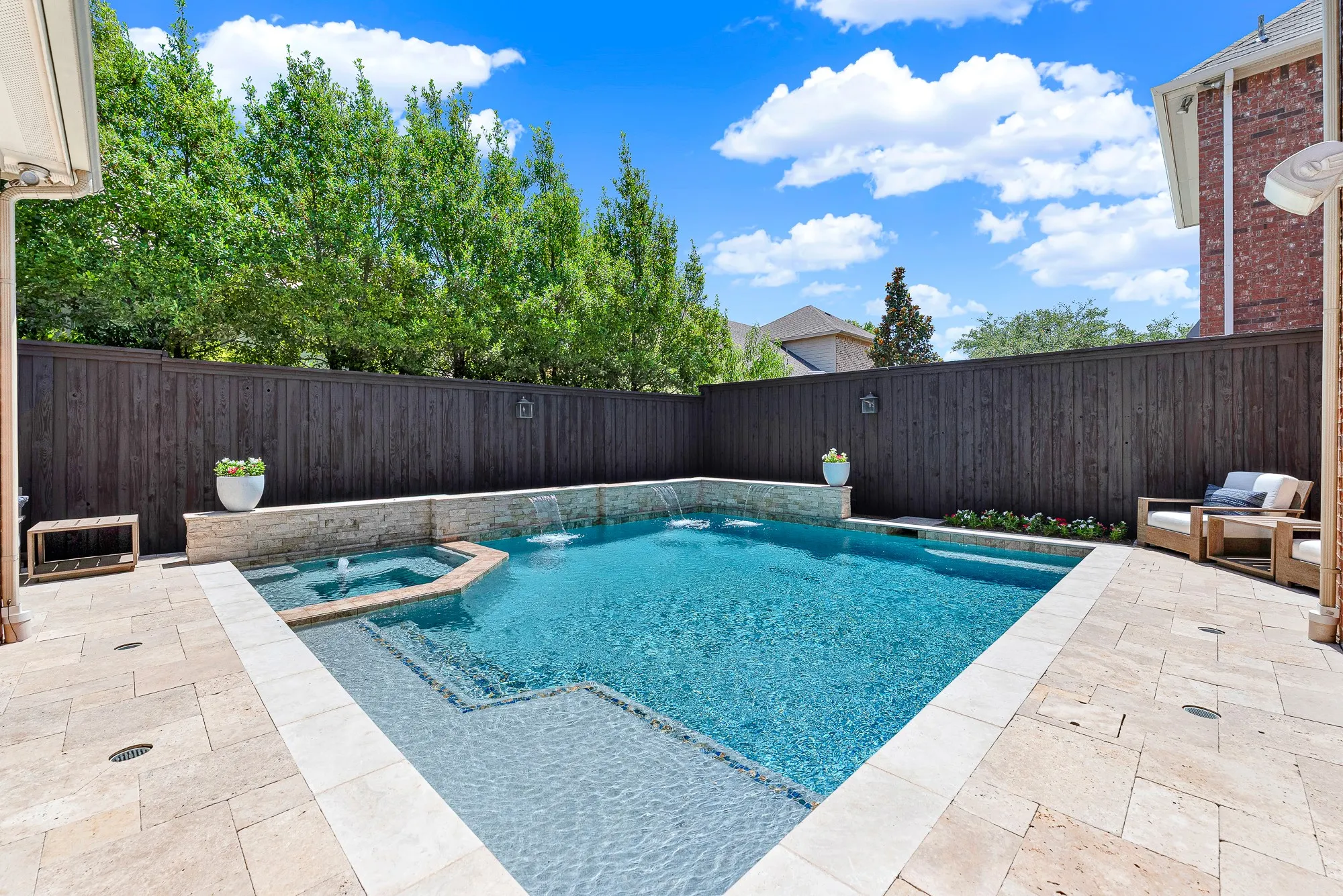 Surrounded by elegant travertine stone decking, this resort-style pool (built 2015) features a wide sun ledge for shallow lounging and water wall fountains. Relax under the sun or cool off in the water while enjoying effortless upkeep thanks to the built-in auto-fill system