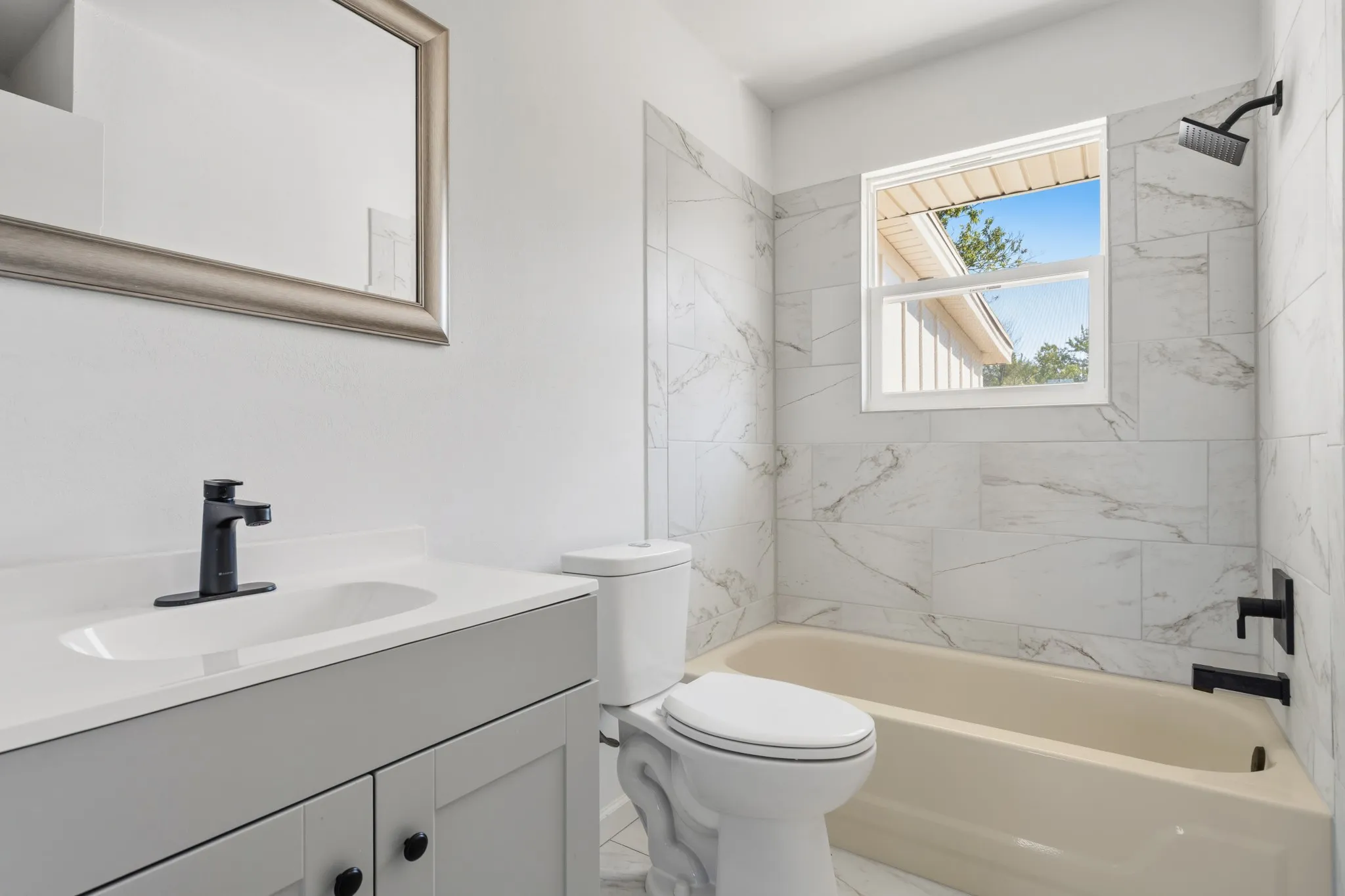 White vanity with a single sink, matte black faucet, and cabinet storage