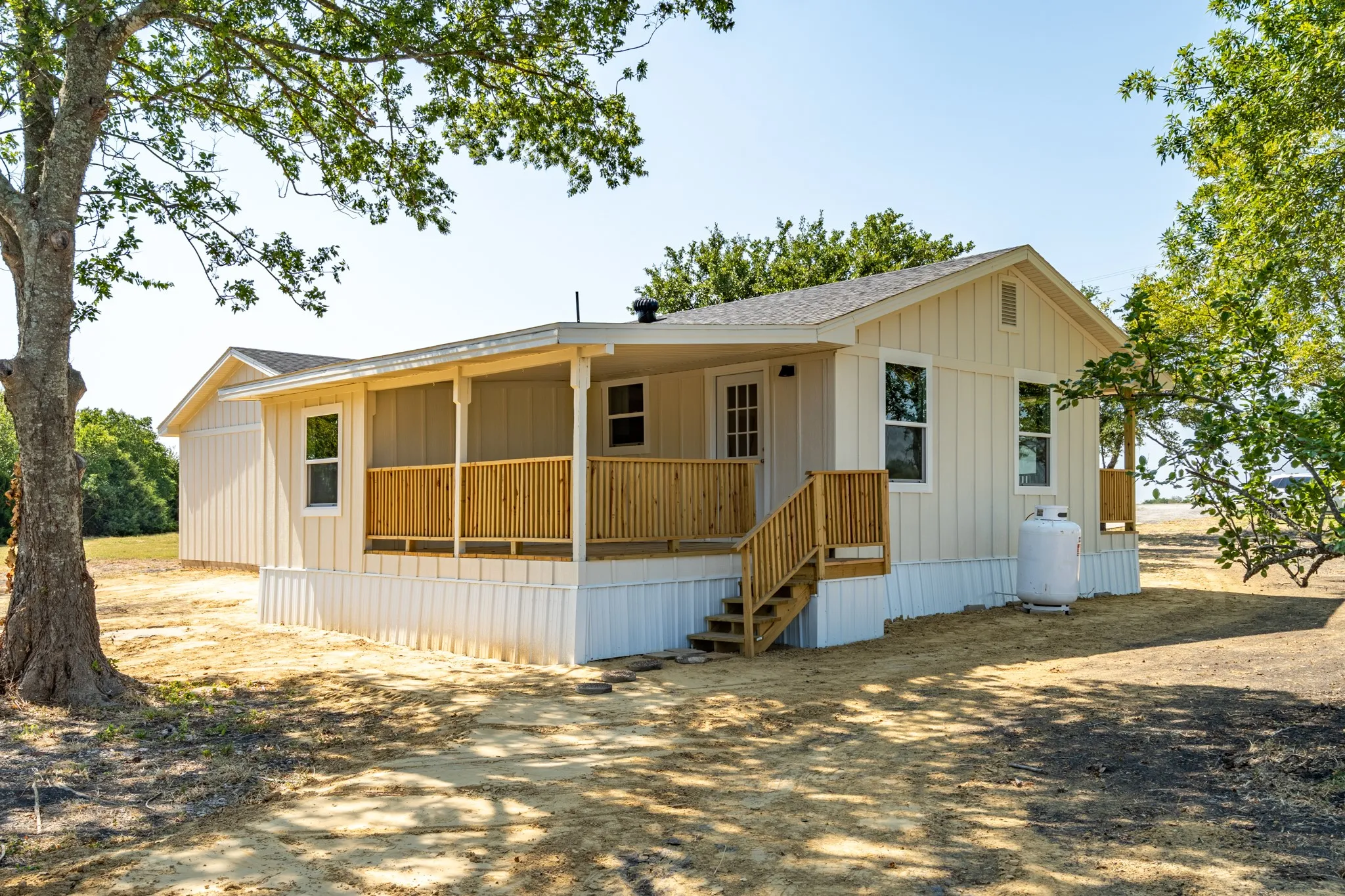 Exterior featuring vertical siding, a covered front porch with natural wood railings, and a side-gabled roof
