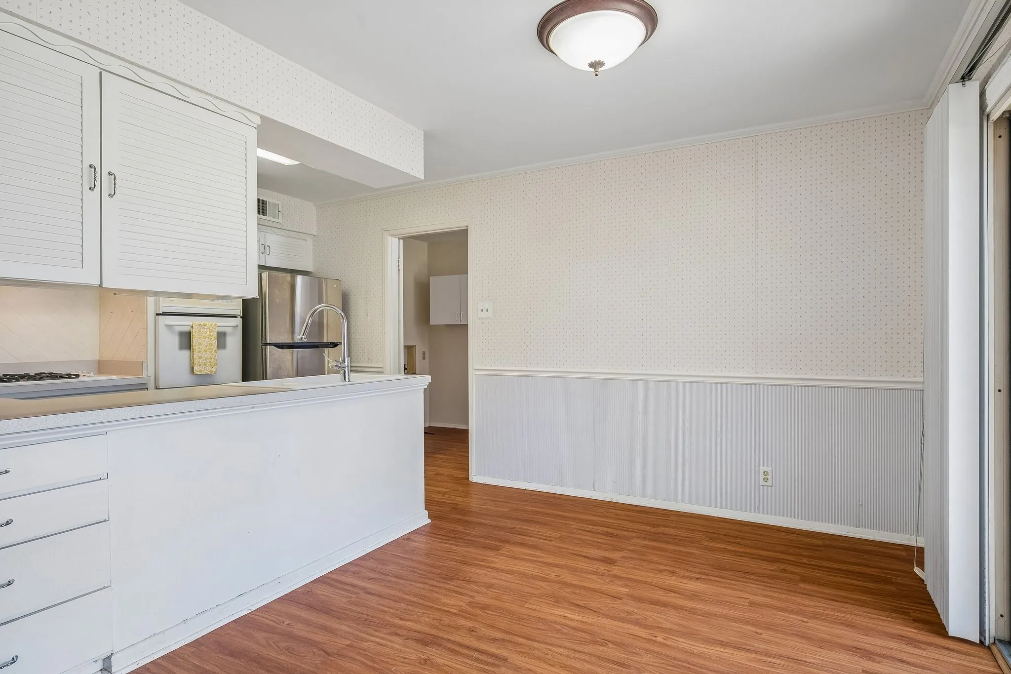 Warm wood toned flooring provides a homey feel throughout the dining, kitchen, and utility areas.