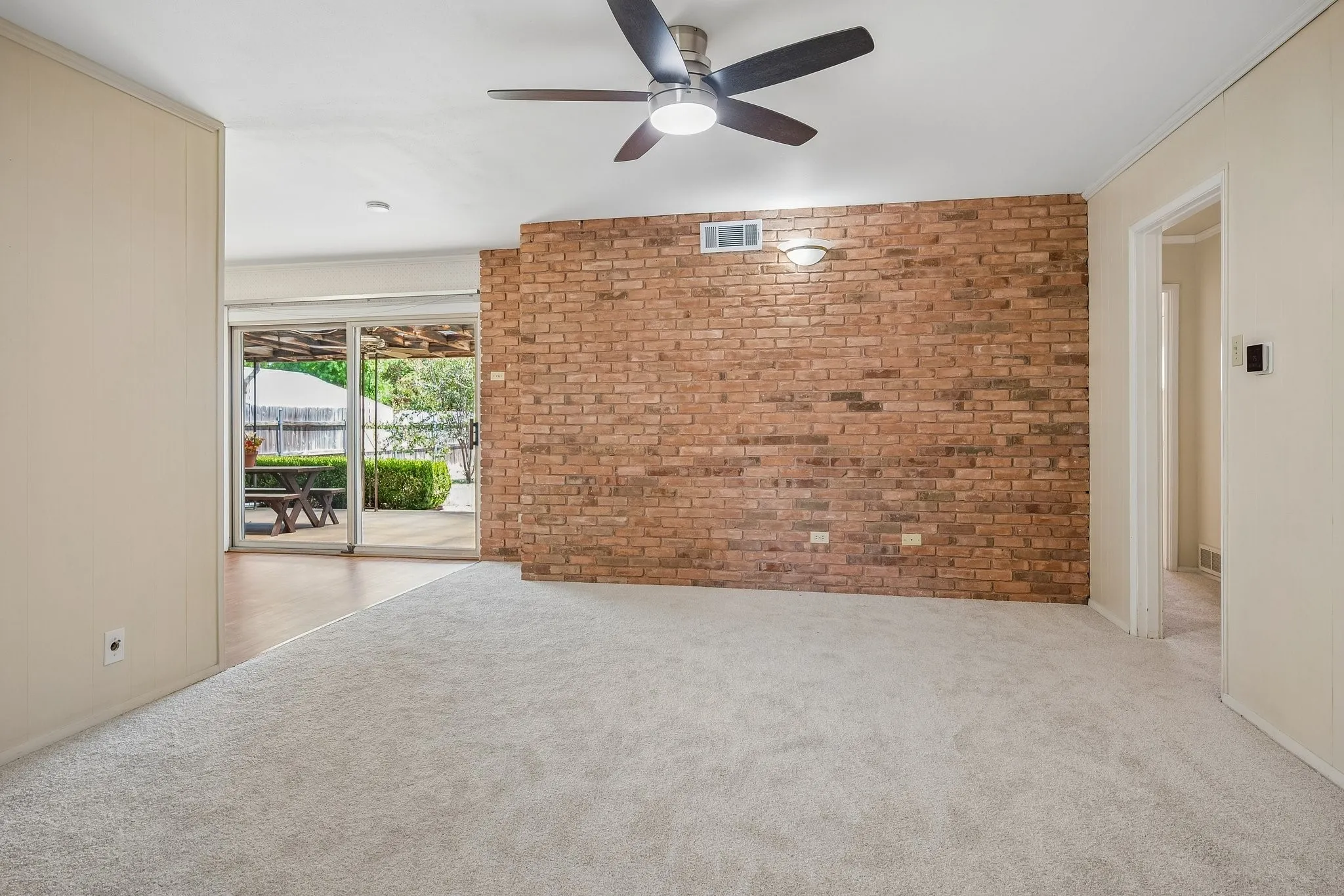 The spacious den is anchored with a warm and aesthetically pleasing floor to ceiling brick wall.