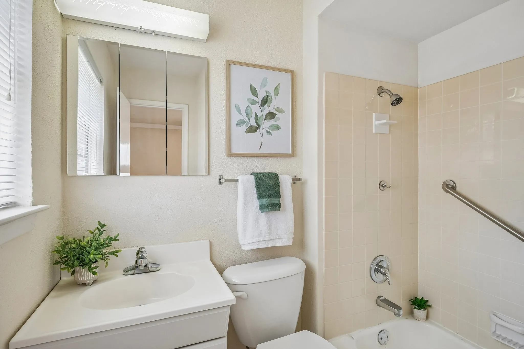 A quaint ensuite bathroom welcomes you with vintage shower tile and soft color tones.