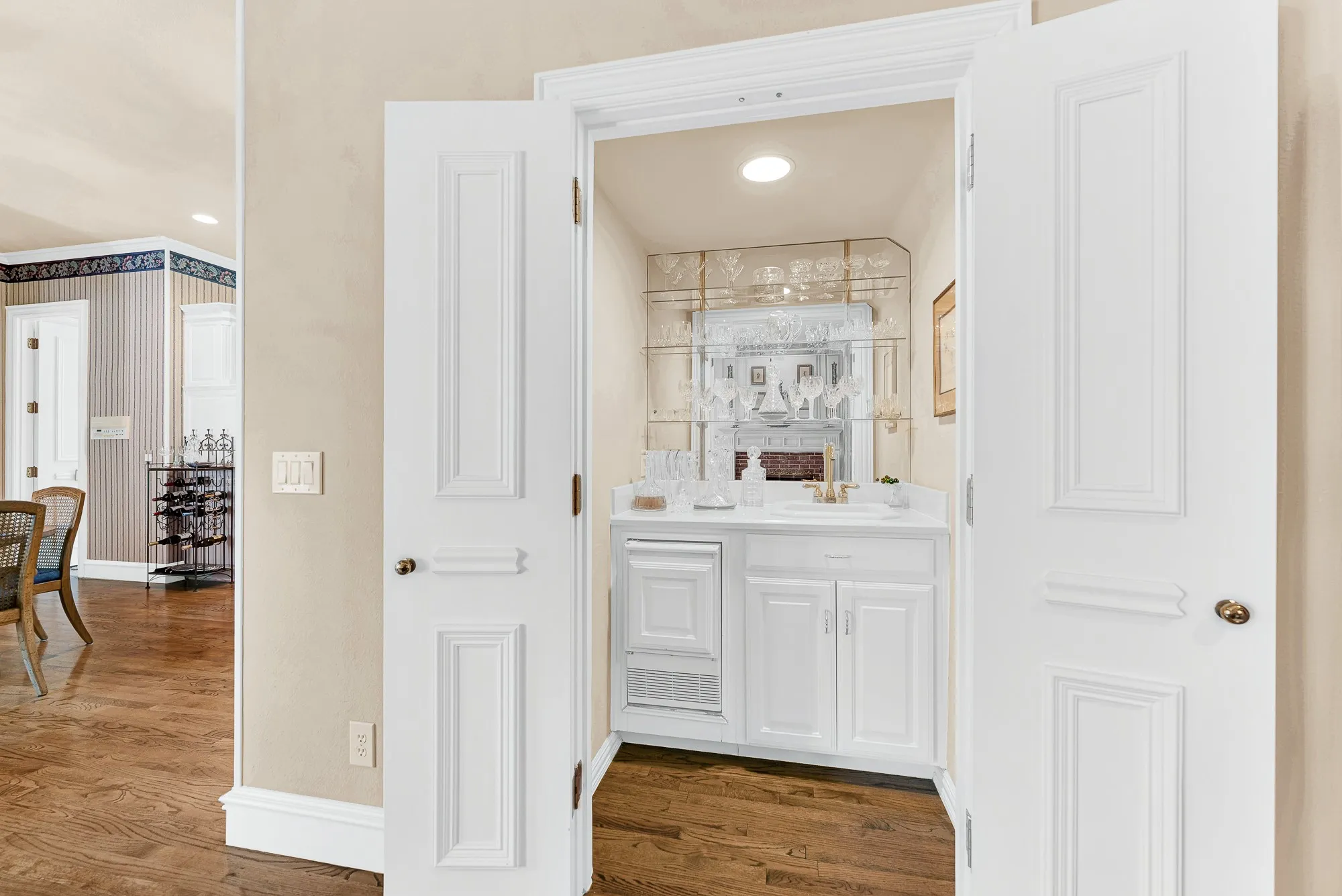 A built-in wet bar tucked behind double doors features delicate glass shelving and an integrated ice machine. Mix craft cocktails here to serve your guests during lively weekend celebrations