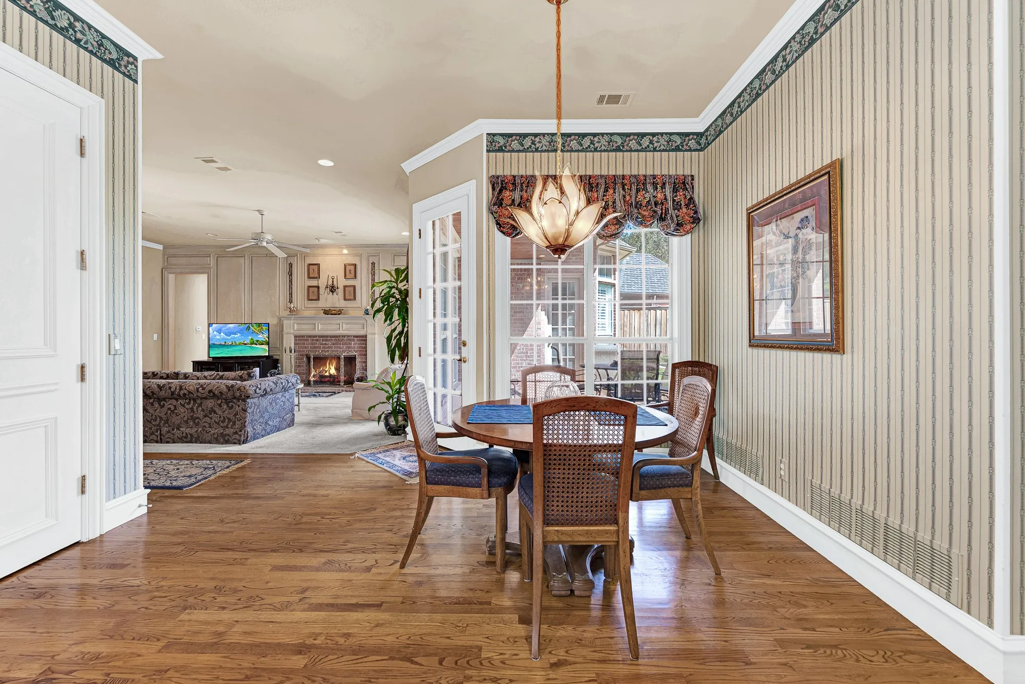 An elegant floral pendant fixture illuminates rich oak flooring, anchoring this cozy dining corner within the open-concept layout. Imagine gathering the family around for quick weekday breakfasts before everyone heads out the door.