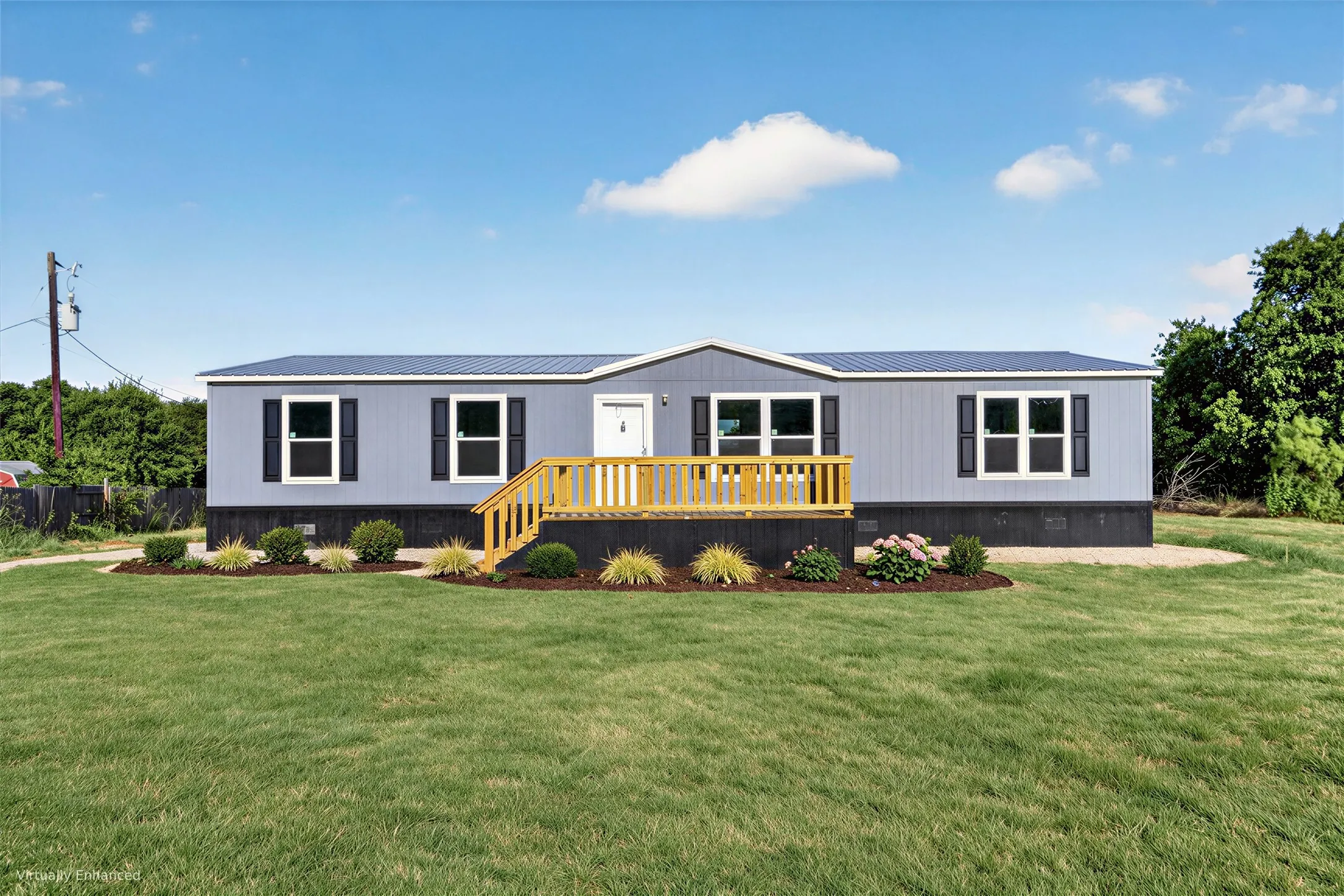Light blue siding exterior with dark shutters, dark metal roof, and a wooden deck entry
