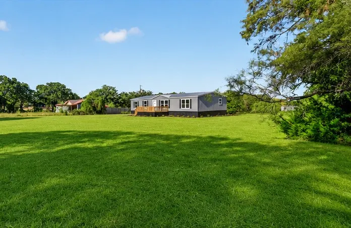 Expansive green lawn surrounding a single-story residence with a front porch.Grass is AI