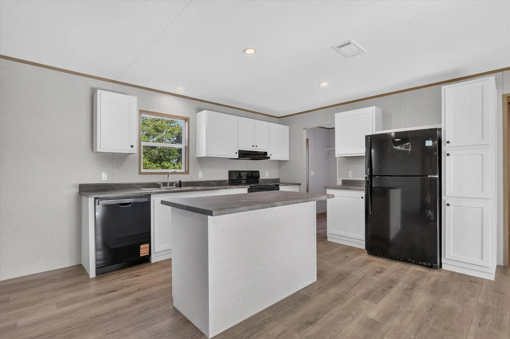 Kitchen featuring white cabinetry, a central island, black appliances, wood-finish flooring, and recessed lighting