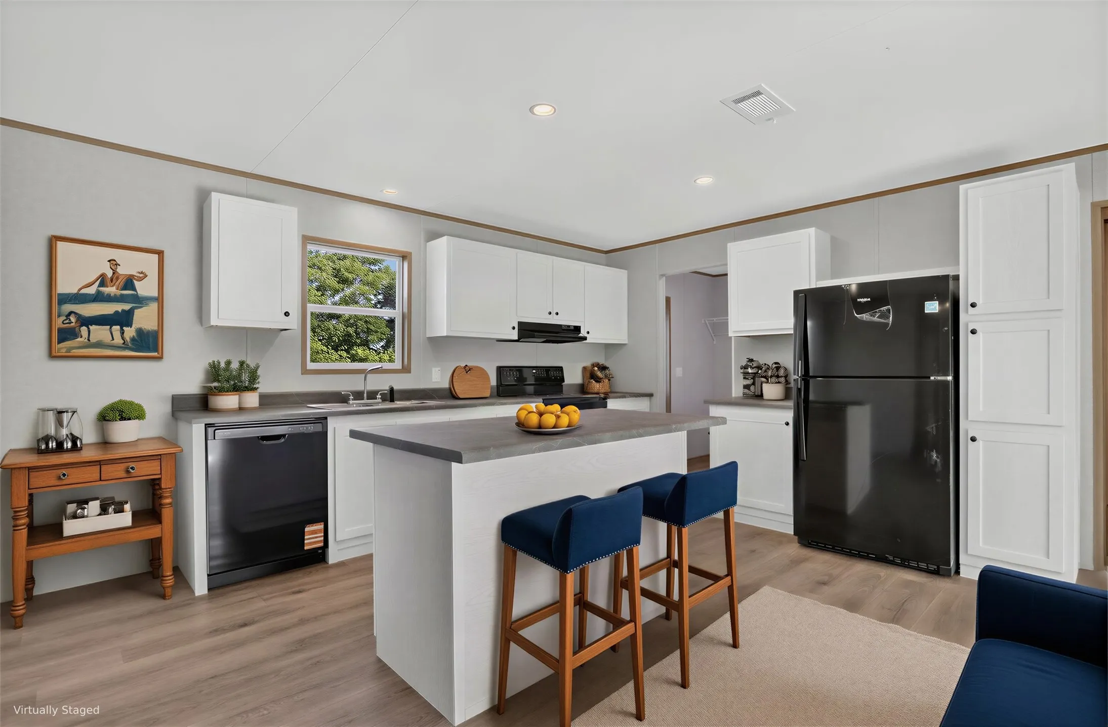 Kitchen featuring a center island recessed lighting, wood-finish flooring, white cabinetry, and a black refrigerator. Furniture is Virtually Staged