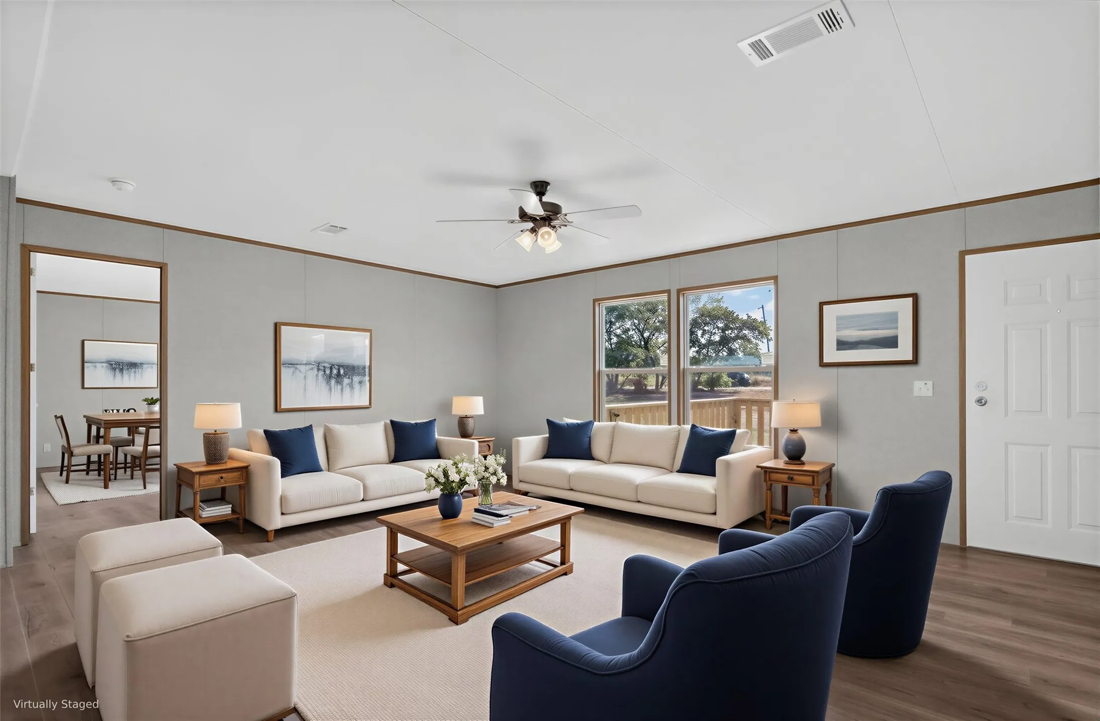 Spacious living area featuring plank flooring, light gray walls, and multiple windows. Furniture is Virtually Staged