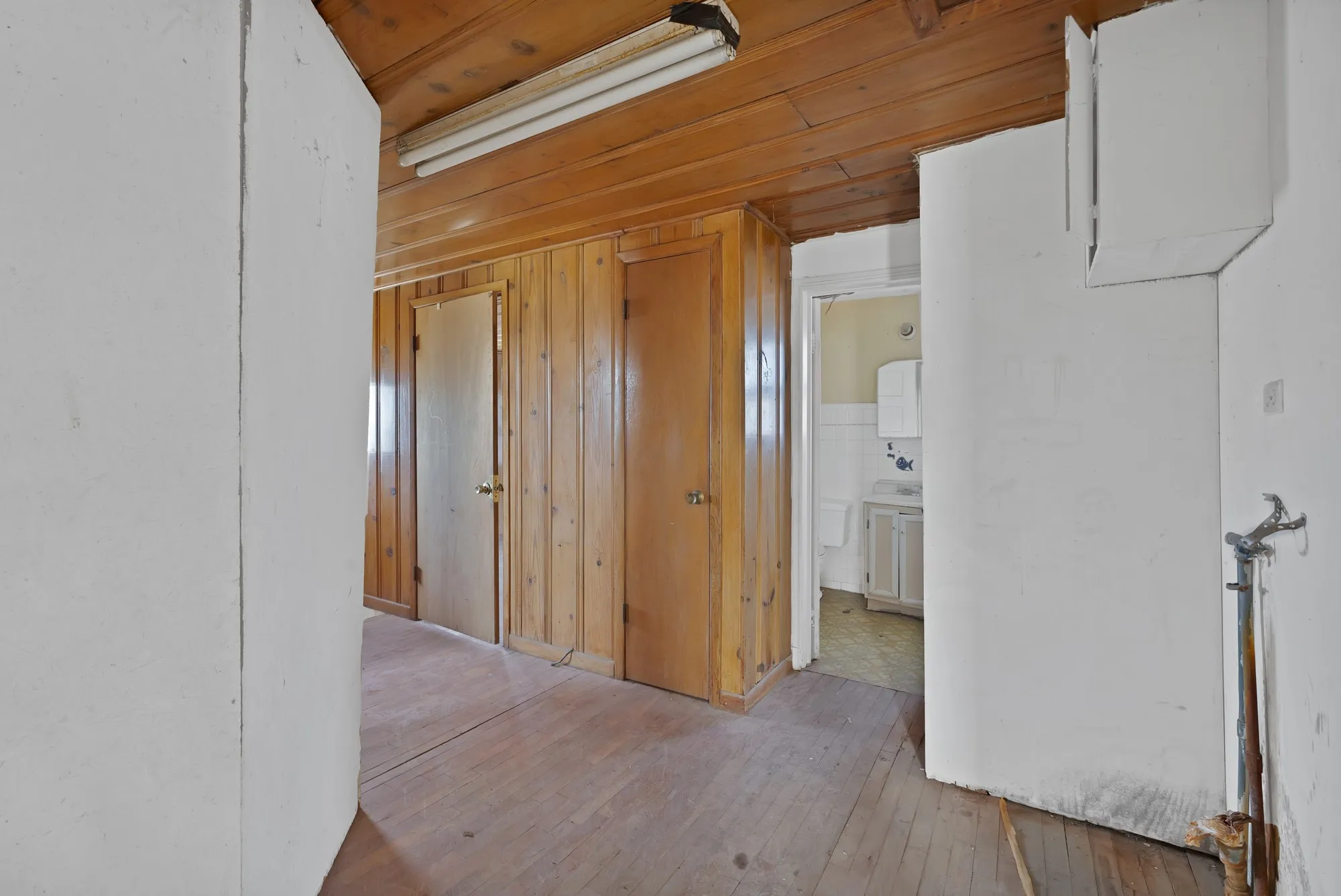 Corridor with light wood-style flooring and wooden walls