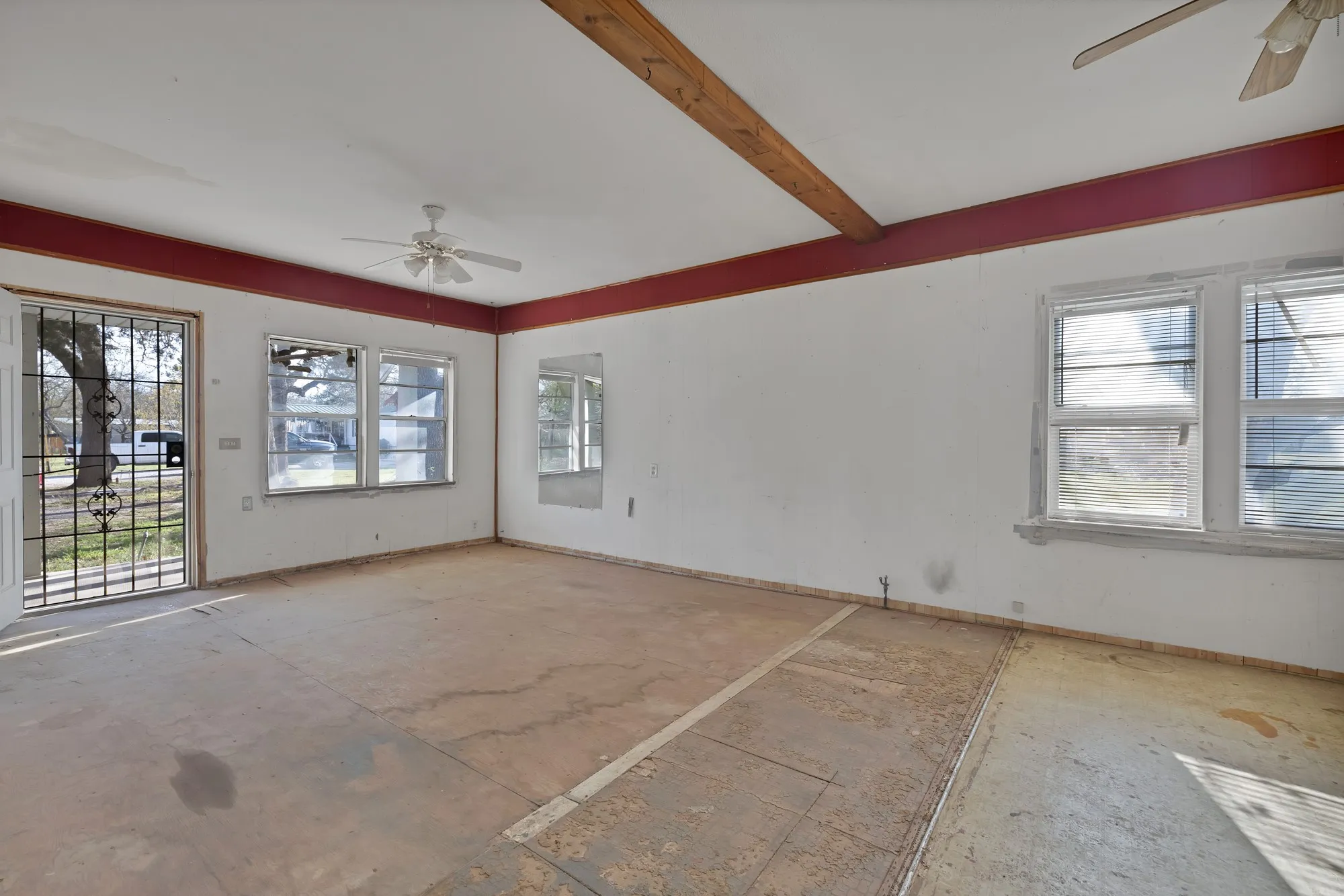 Empty room with a ceiling fan and beamed ceiling