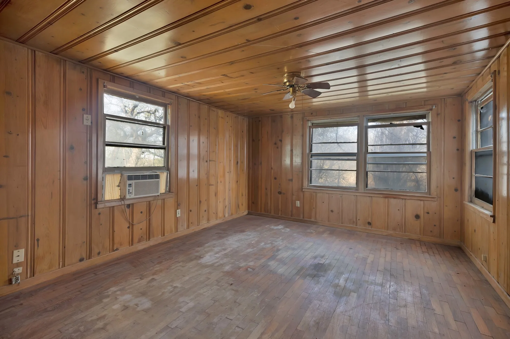 Spare room featuring dark wood-type flooring, wooden walls, a ceiling fan, cooling unit, and wooden ceiling