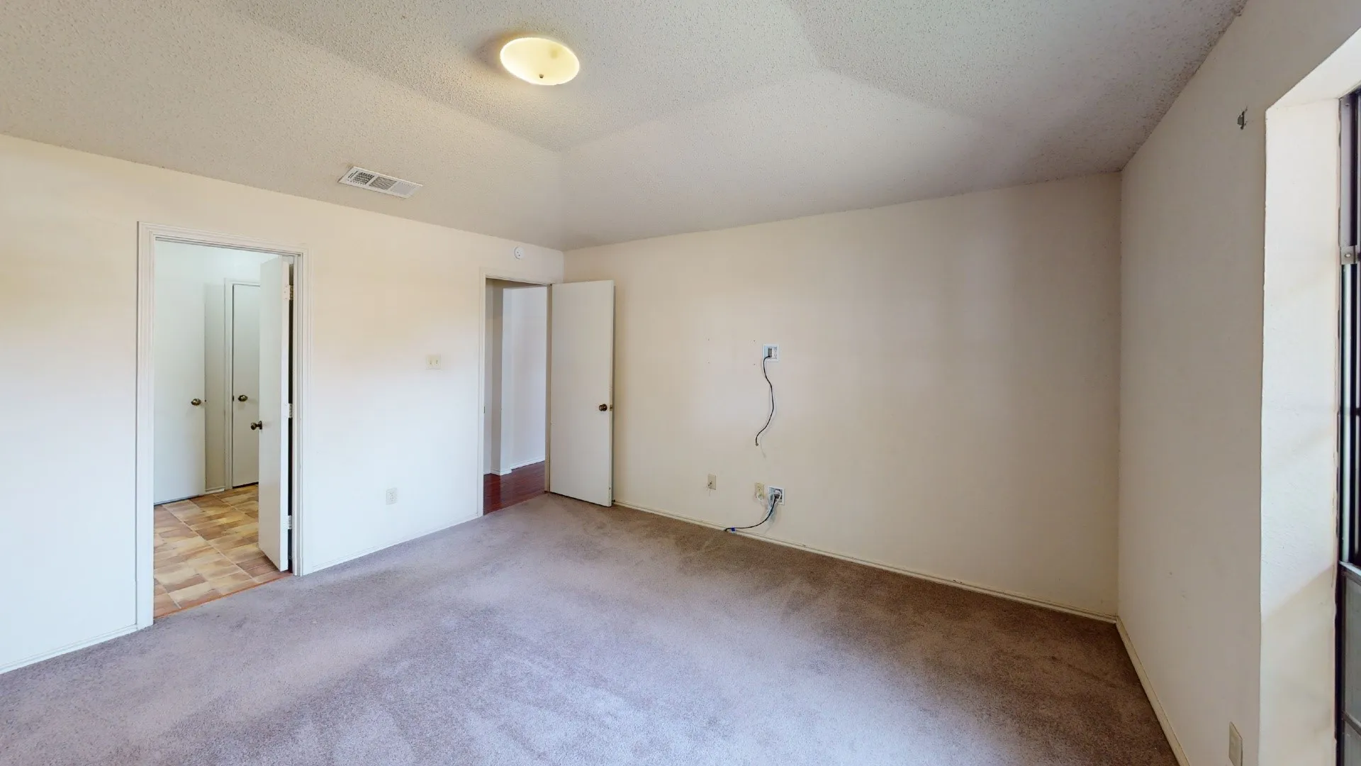 Carpeted flooring, white interior walls, and an overhead flush-mount light fixture