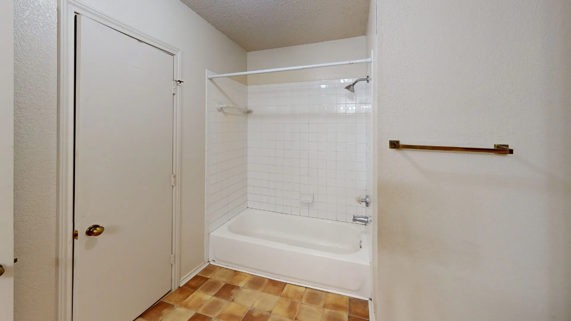 White shower-over-tub combination with subway tile surround and a bronze towel bar