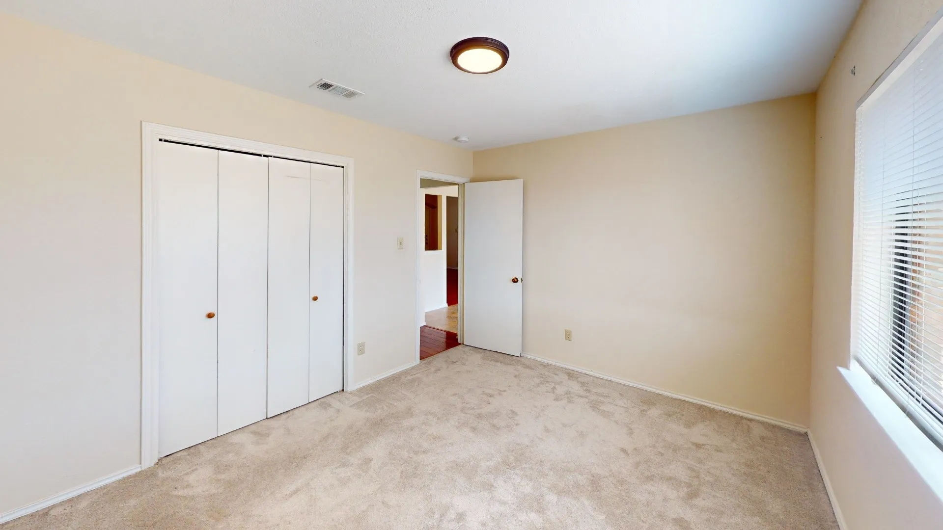 Neutral-toned walls, carpeted flooring, and a flush mount ceiling light fixture