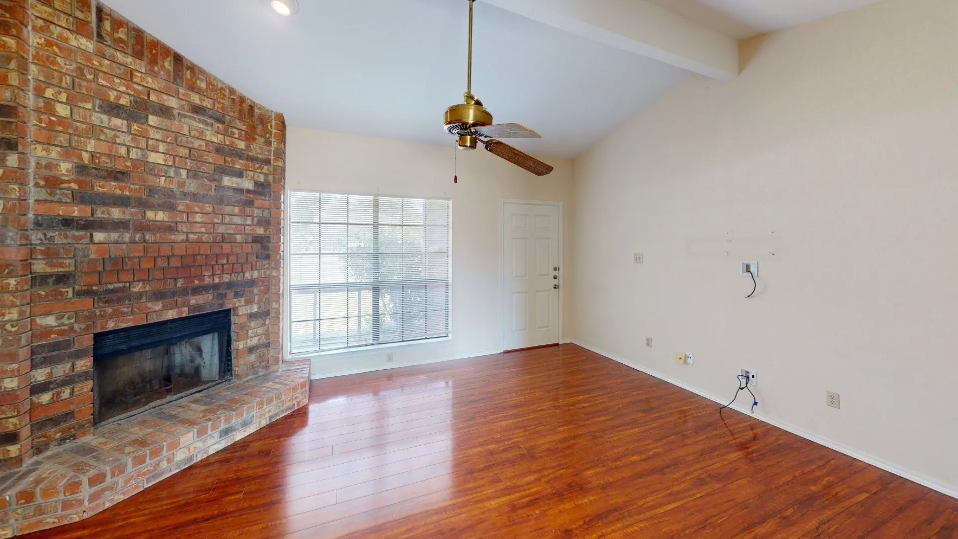 Living space featuring a brick fireplace, wood-finish flooring, vaulted ceiling, multi-pane window, and a ceiling fan