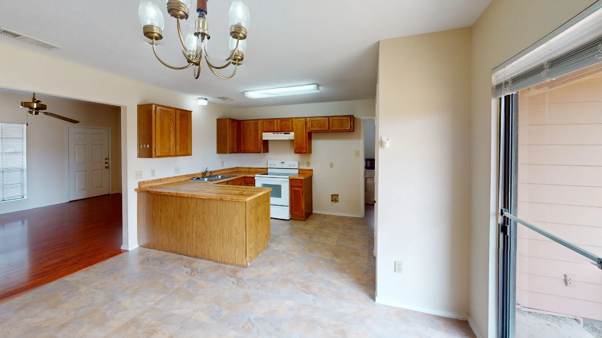 Open-concept kitchen with wood-finish cabinetry, U-shaped countertops, and white appliances