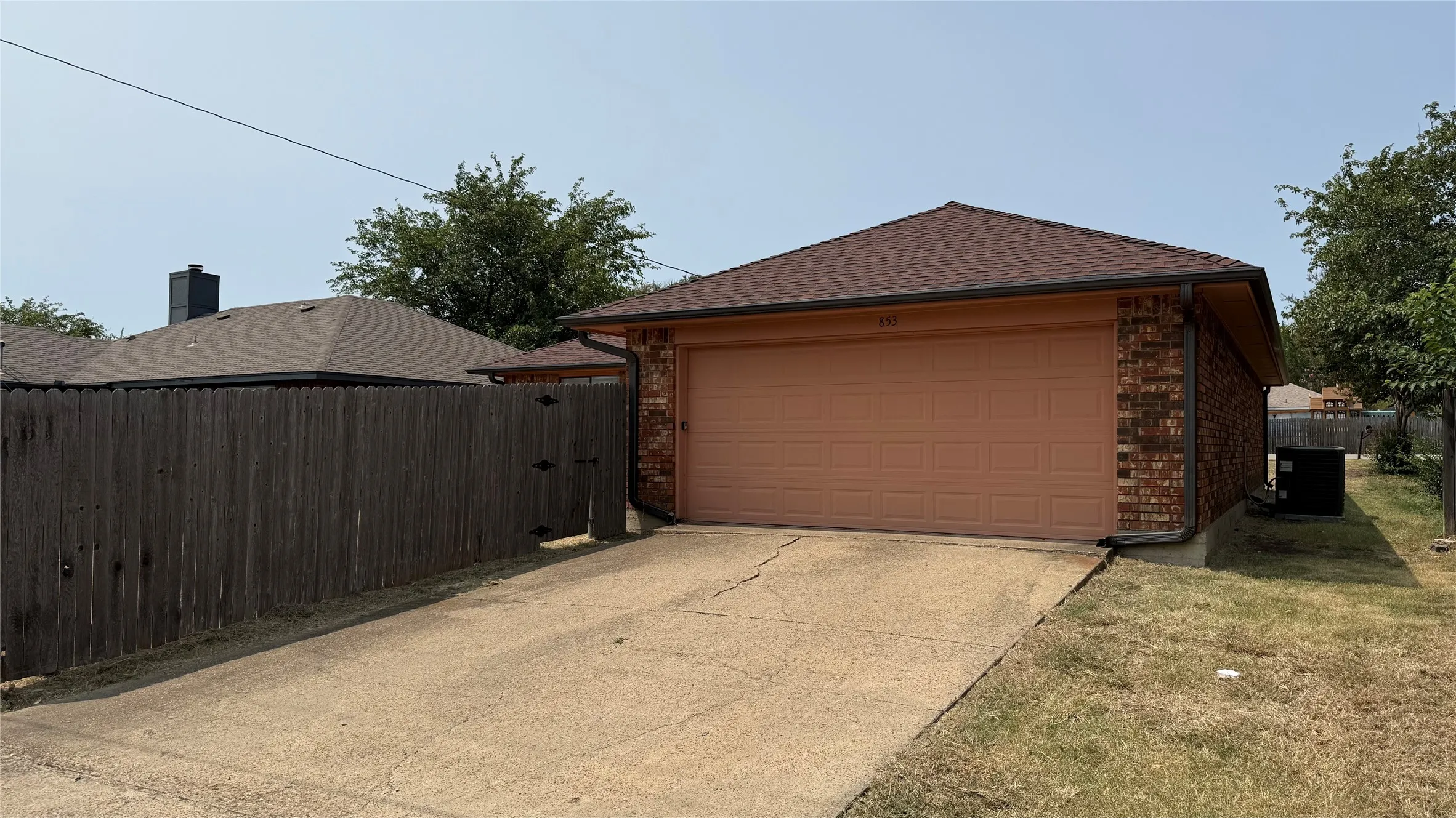 Brick exterior with a two-car garage, concrete driveway, and brown shingle roof