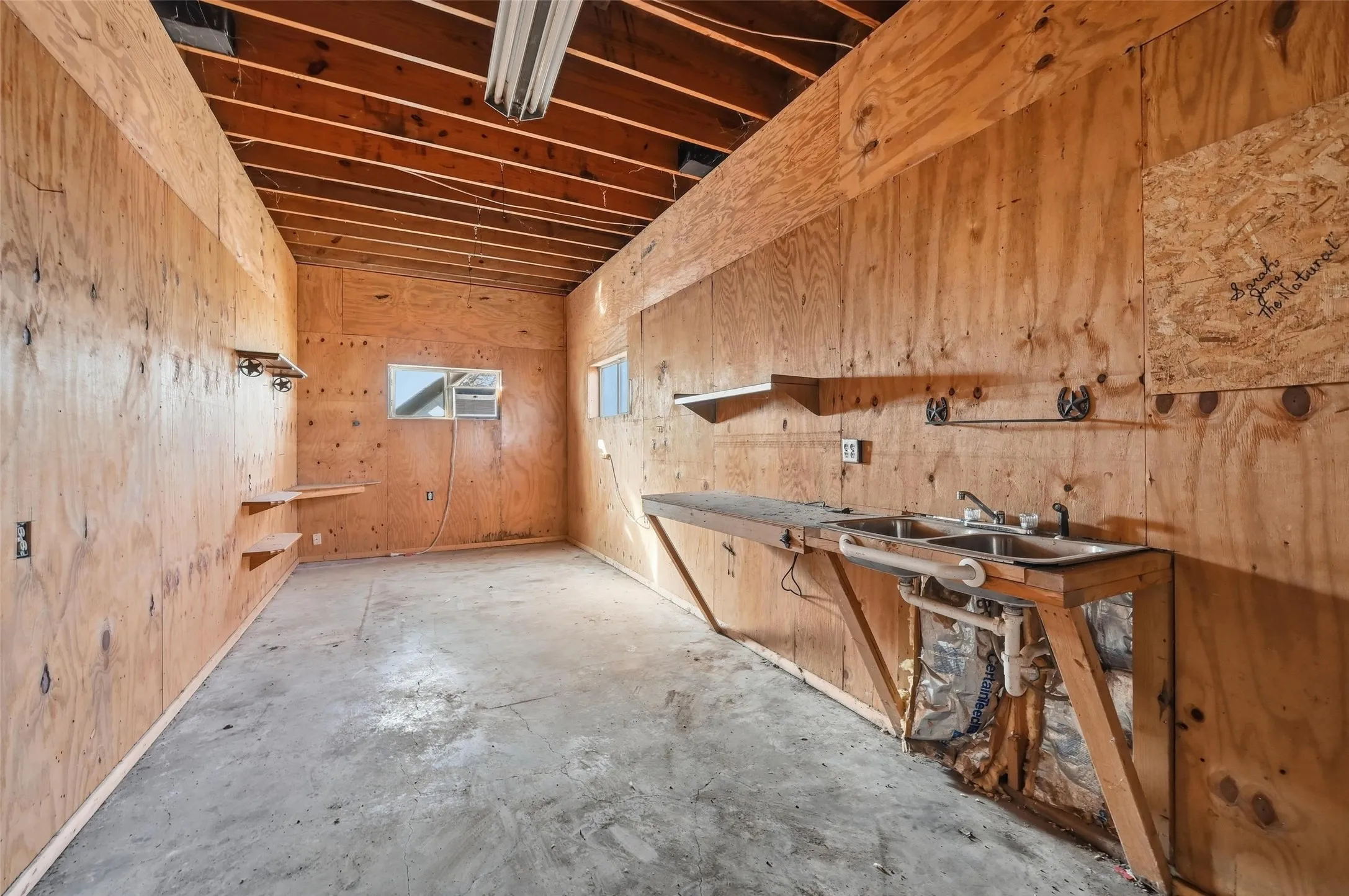 Misc room featuring unfinished concrete floors and wooden walls