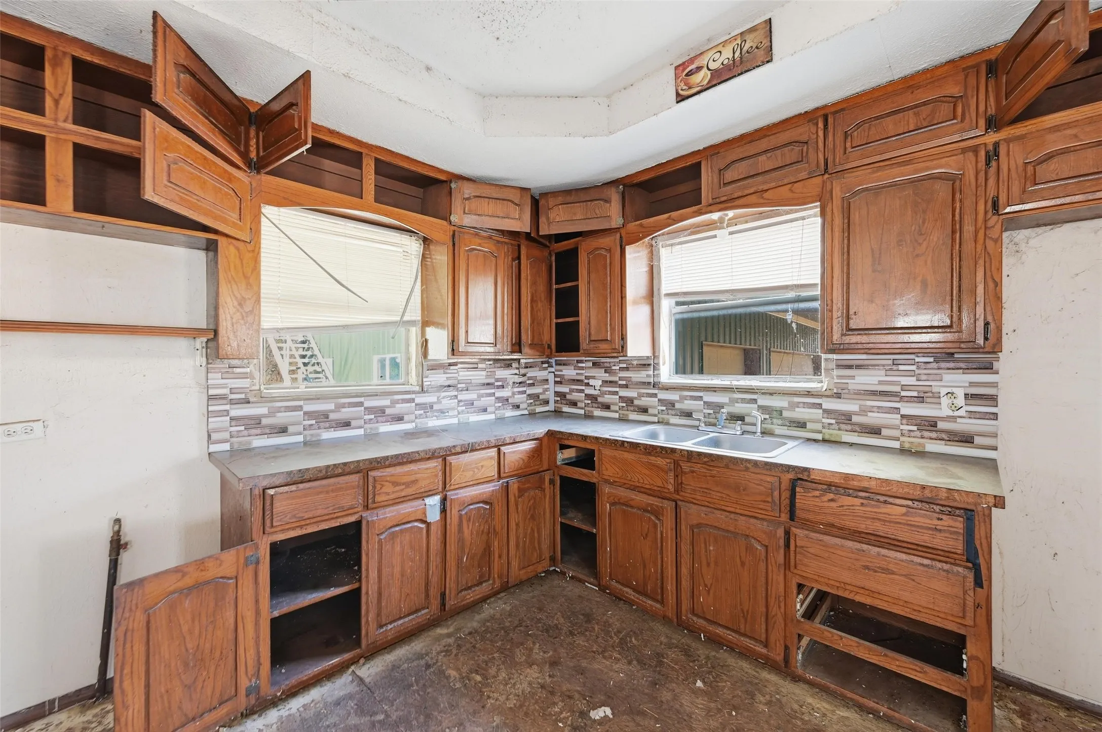 Kitchen with brown cabinetry, open shelves, tasteful backsplash, light countertops, and a tray ceiling