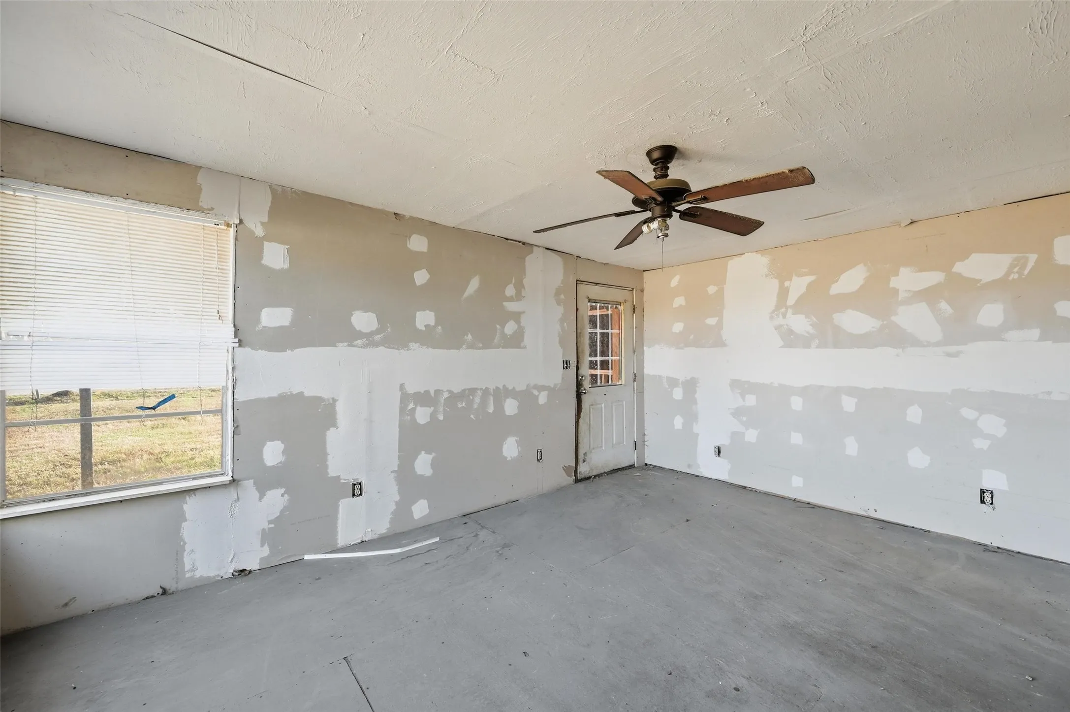 Empty room with a ceiling fan and a textured ceiling