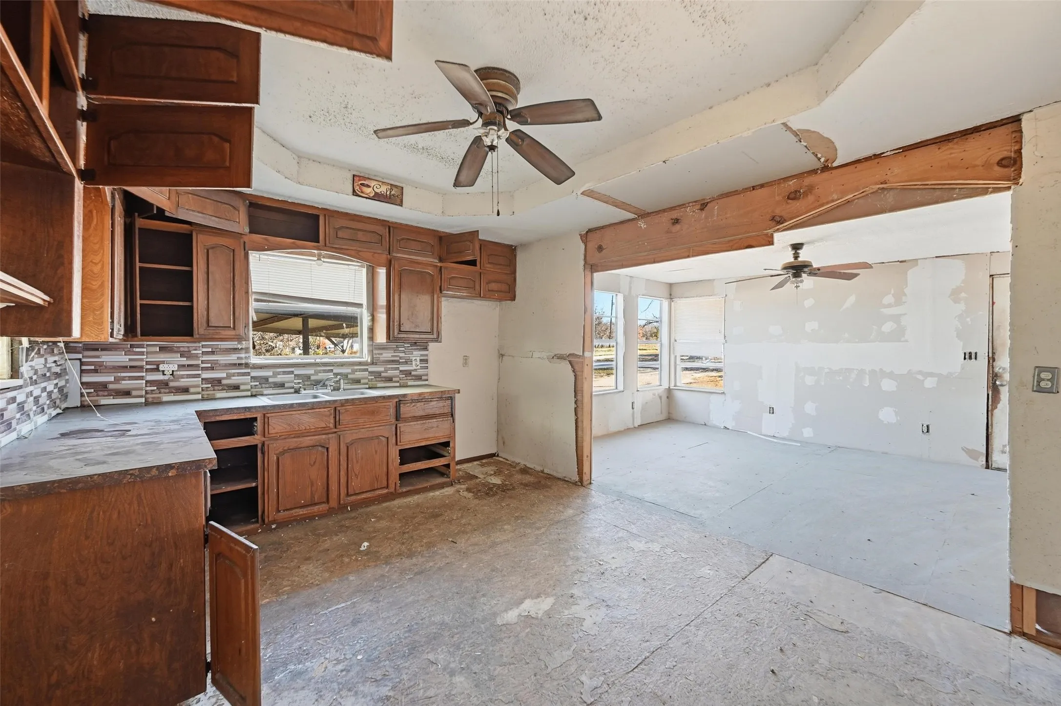 Kitchen with brown cabinetry, a ceiling fan, light countertops, and a textured ceiling