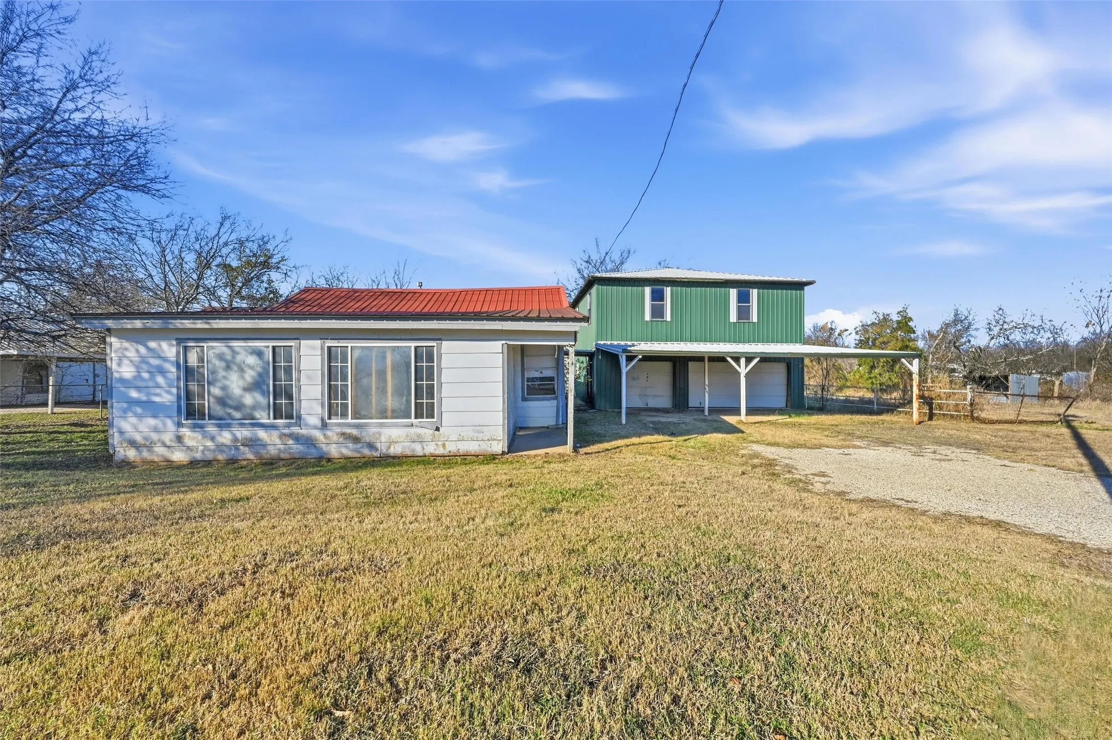 View of front facade with driveway, a metal roof, and a garage