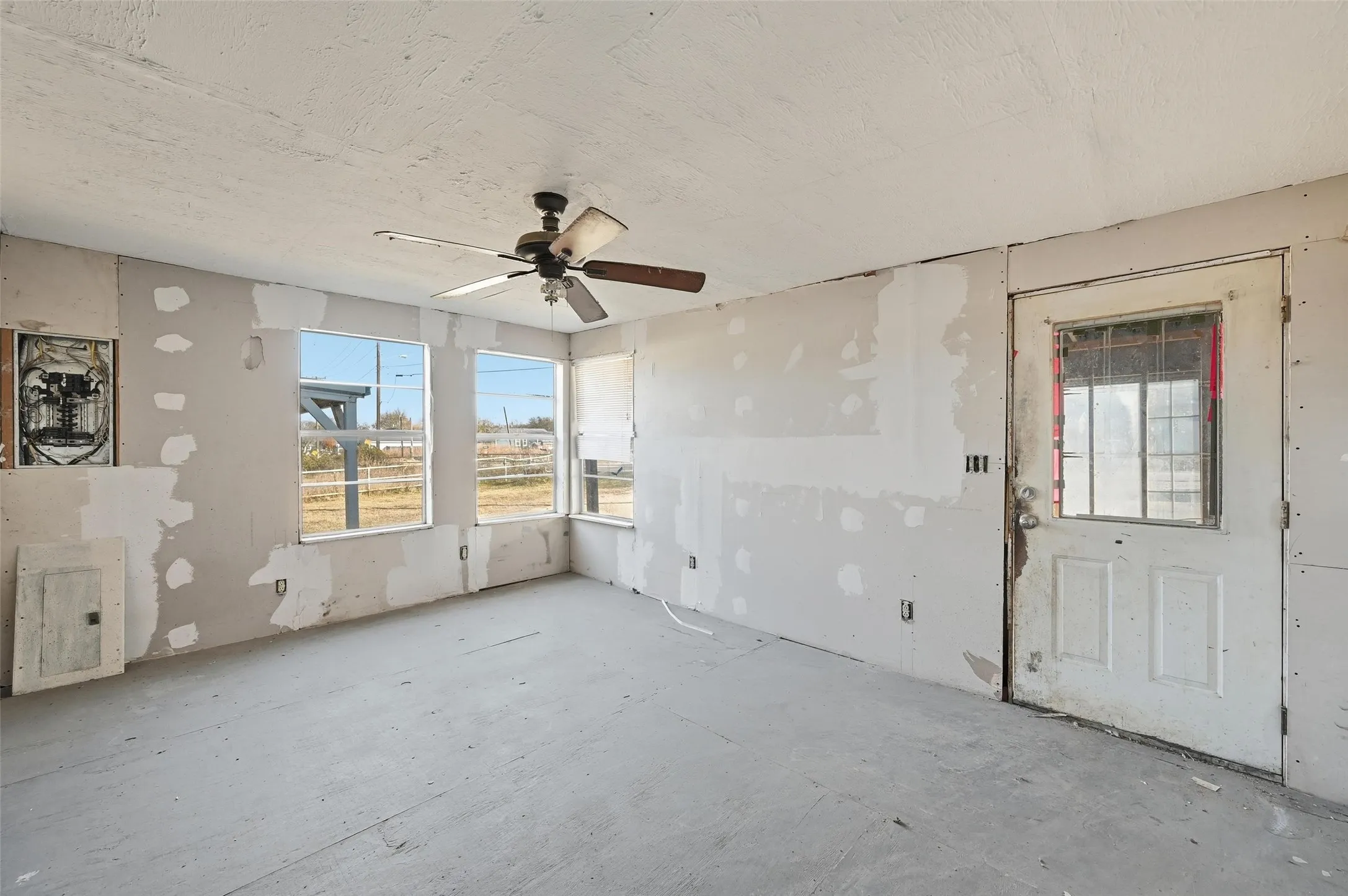 Empty room with a textured ceiling and ceiling fan