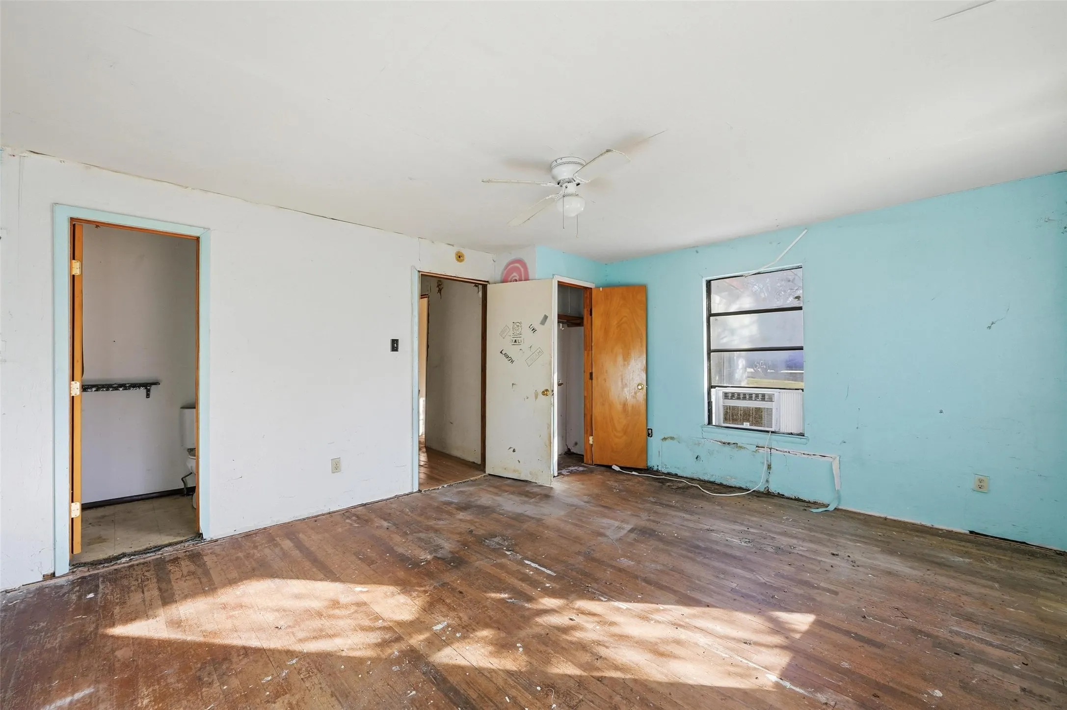Unfurnished bedroom with a ceiling fan, wood-type flooring, and ensuite bathroom