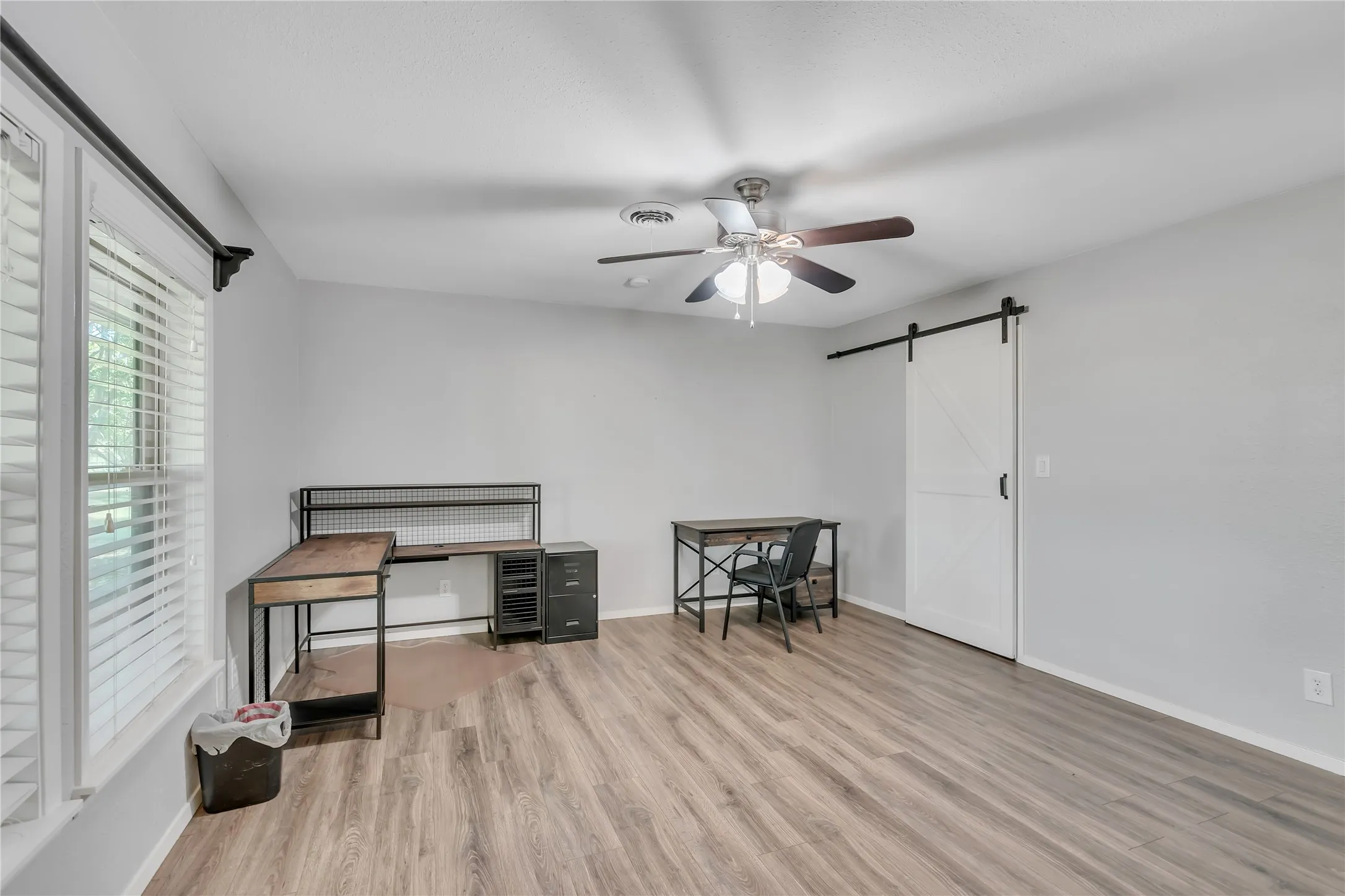 Wood-finish flooring, white walls, and a ceiling fan with integrated lighting