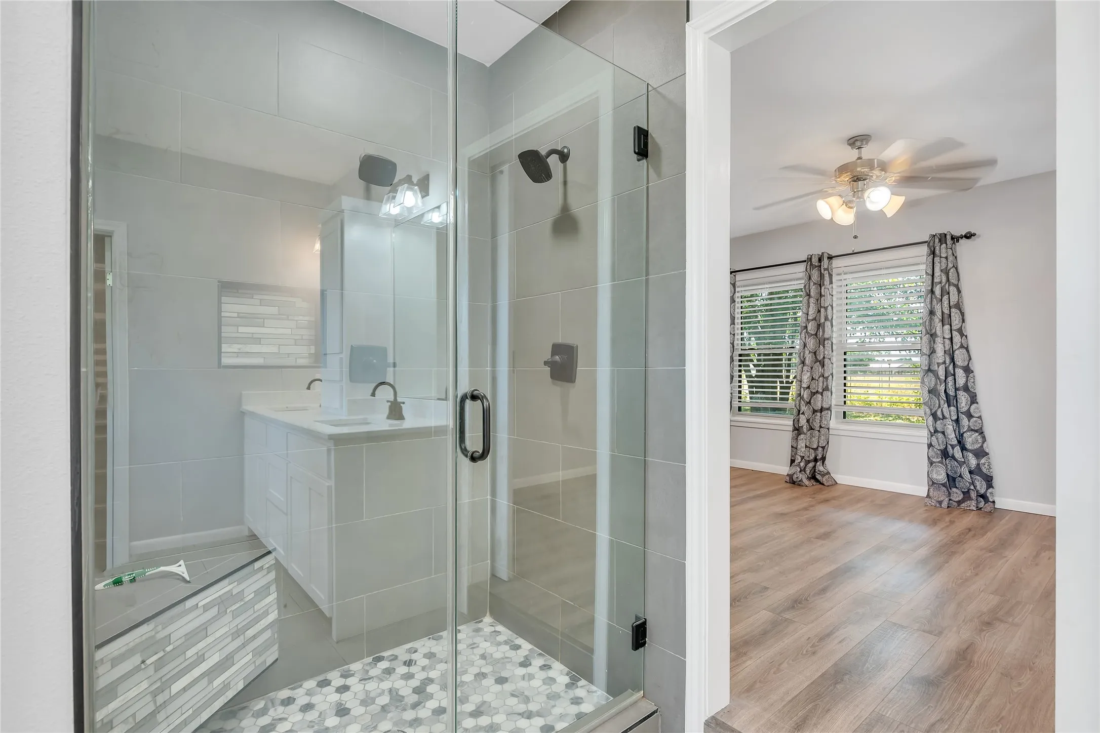 Glass-enclosed shower with a tiled bench and hexagonal floor tiles