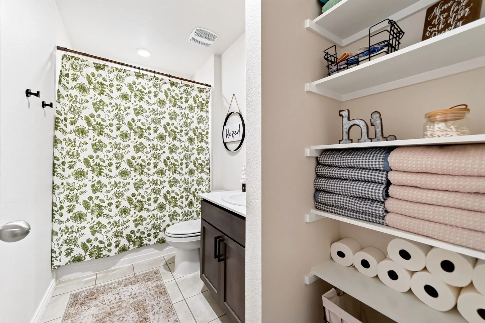 Recessed lighting, wood-finish vanity with a rectangular sink, tile flooring, built-in shelving, and wall-mounted towel hooks