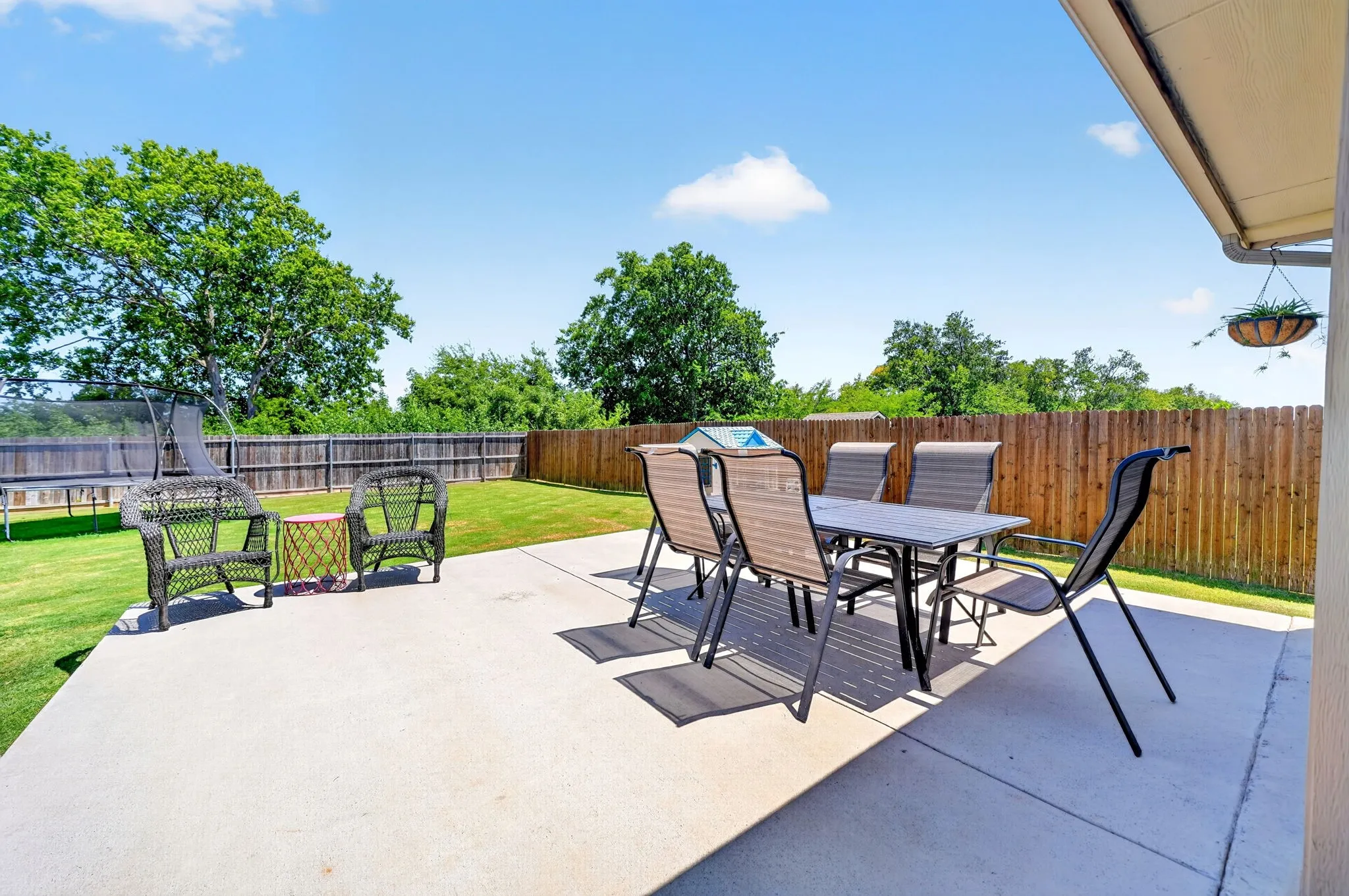 Expansive concrete patio with a manicured lawn and a privacy fence