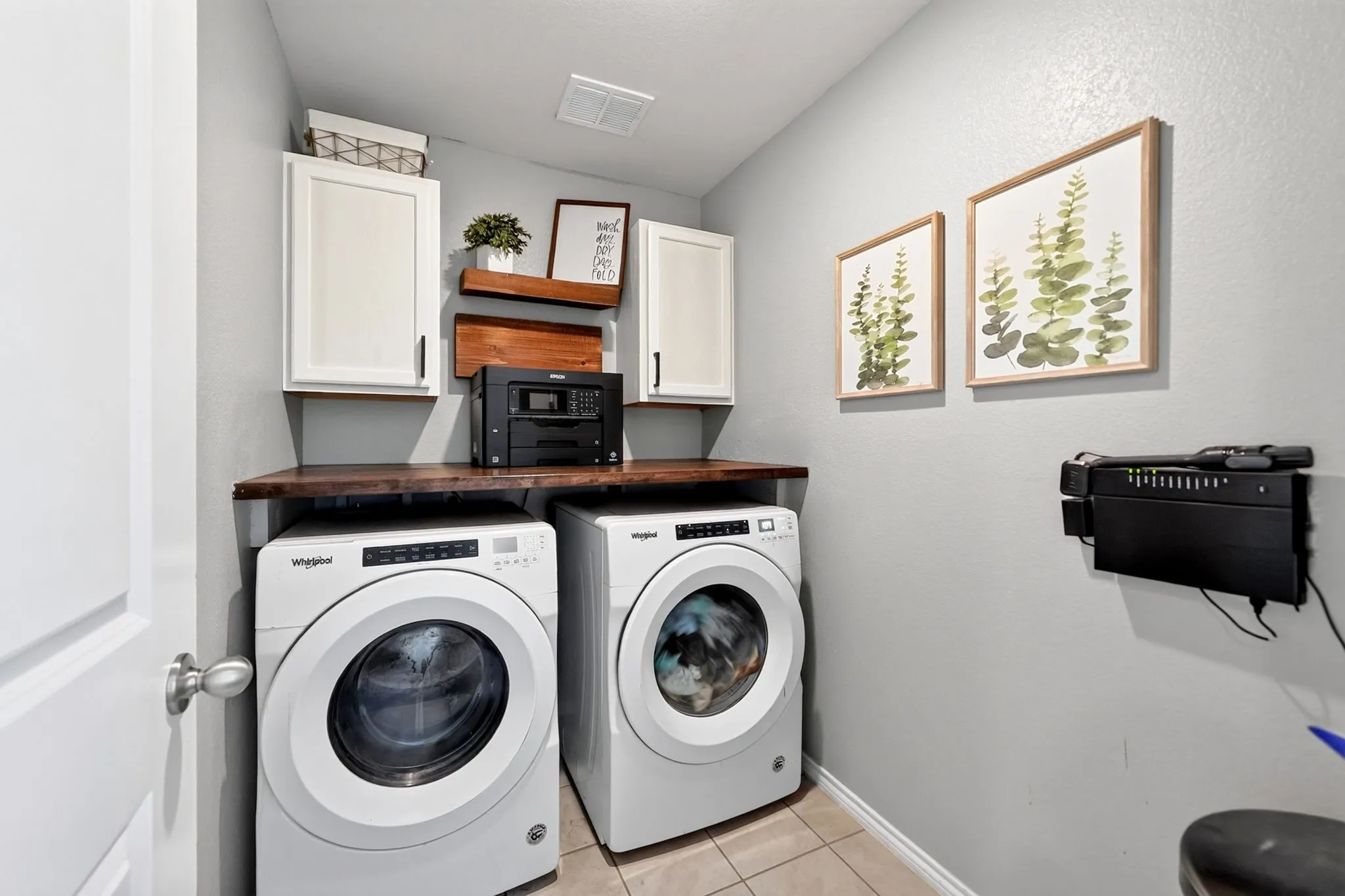 Laundry area featuring a wood-finish countertop, white cabinetry with dark hardware, and two wood-finish wall shelves