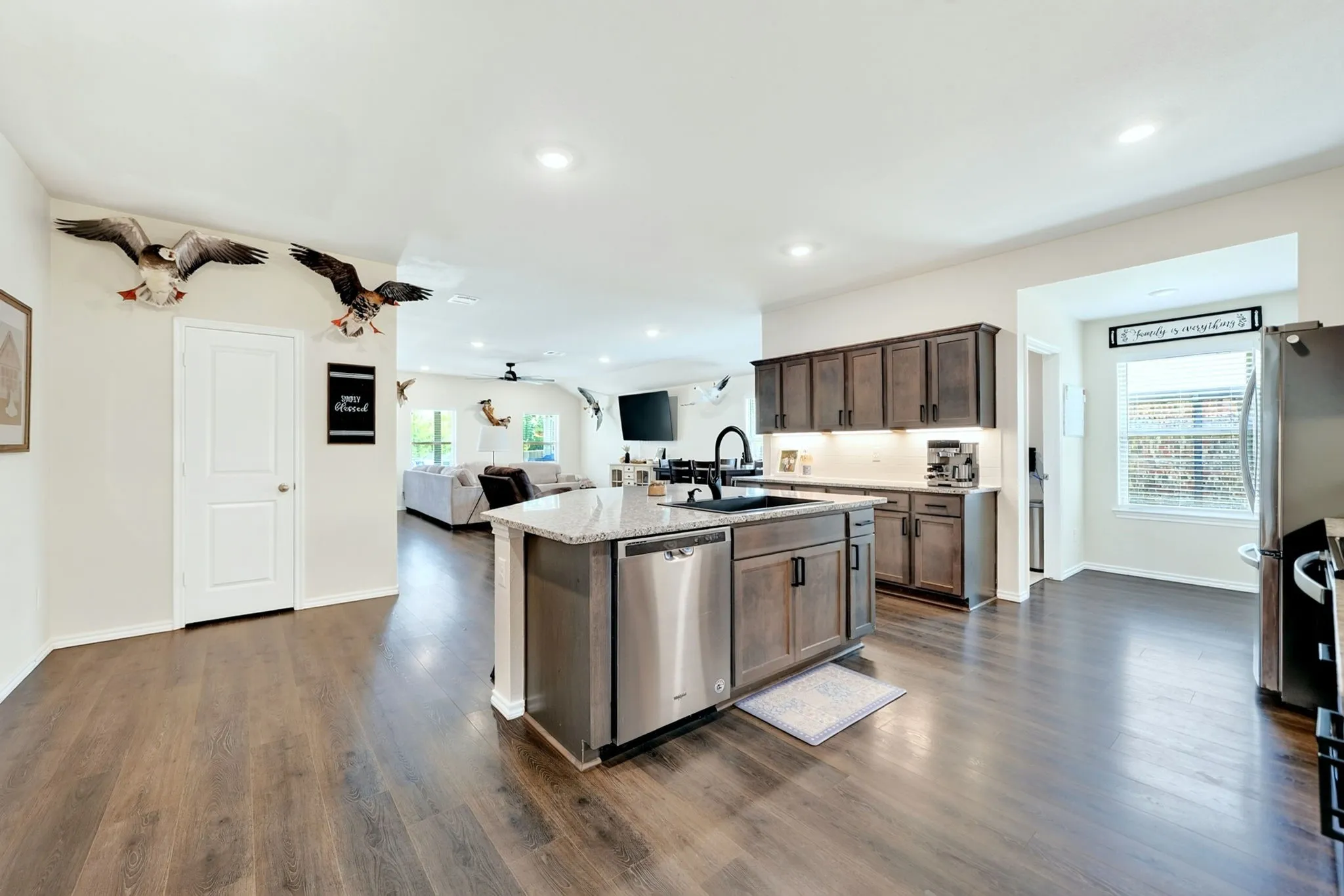 Kitchen featuring a central island with an undermount sink, stainless steel appliances, dark wood-finish cabinetry, and wood-finish flooring