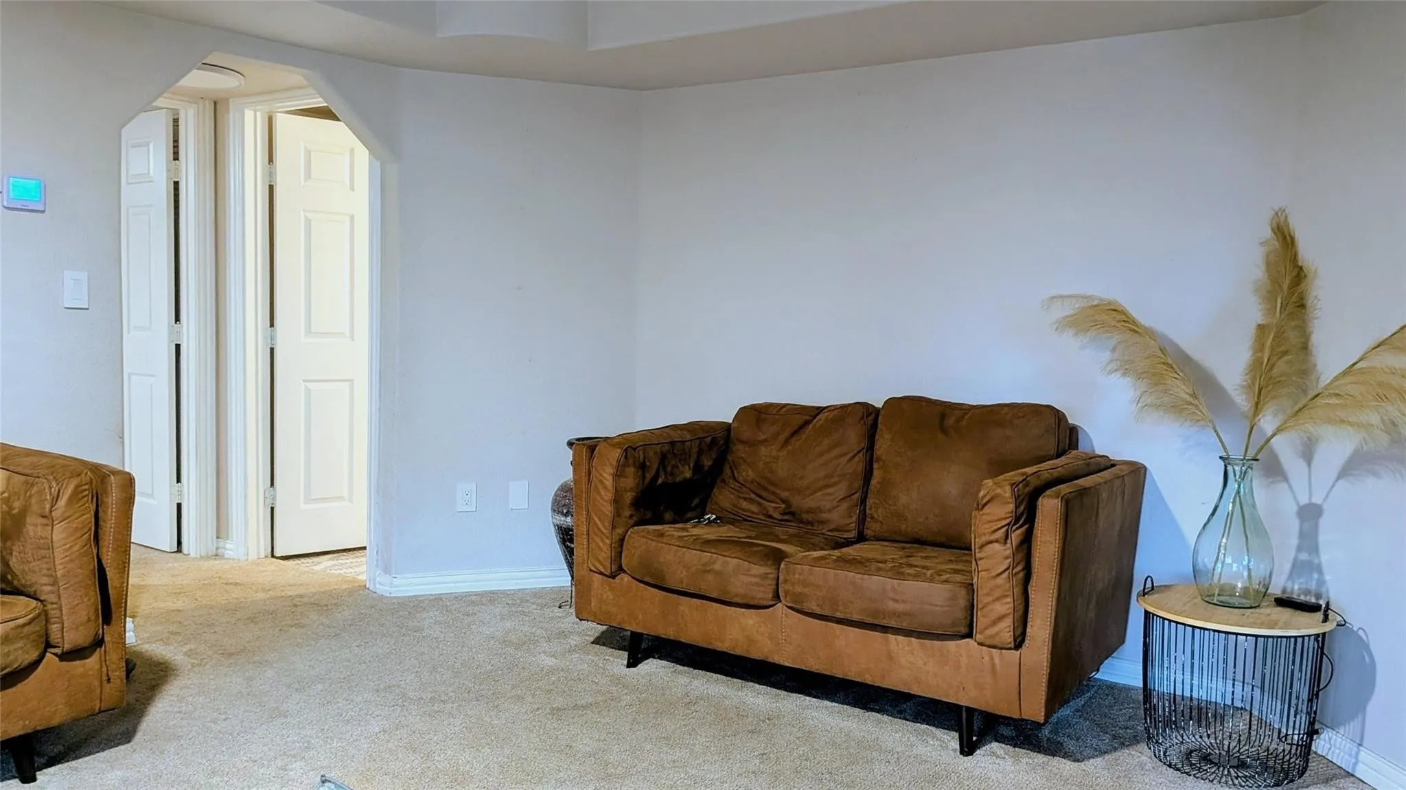 Carpeted flooring, white walls, and an arched entryway