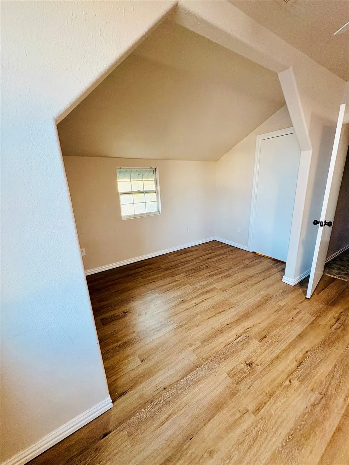 Room featuring laminate finish flooring, a window with gridded panes, and a white paneled door