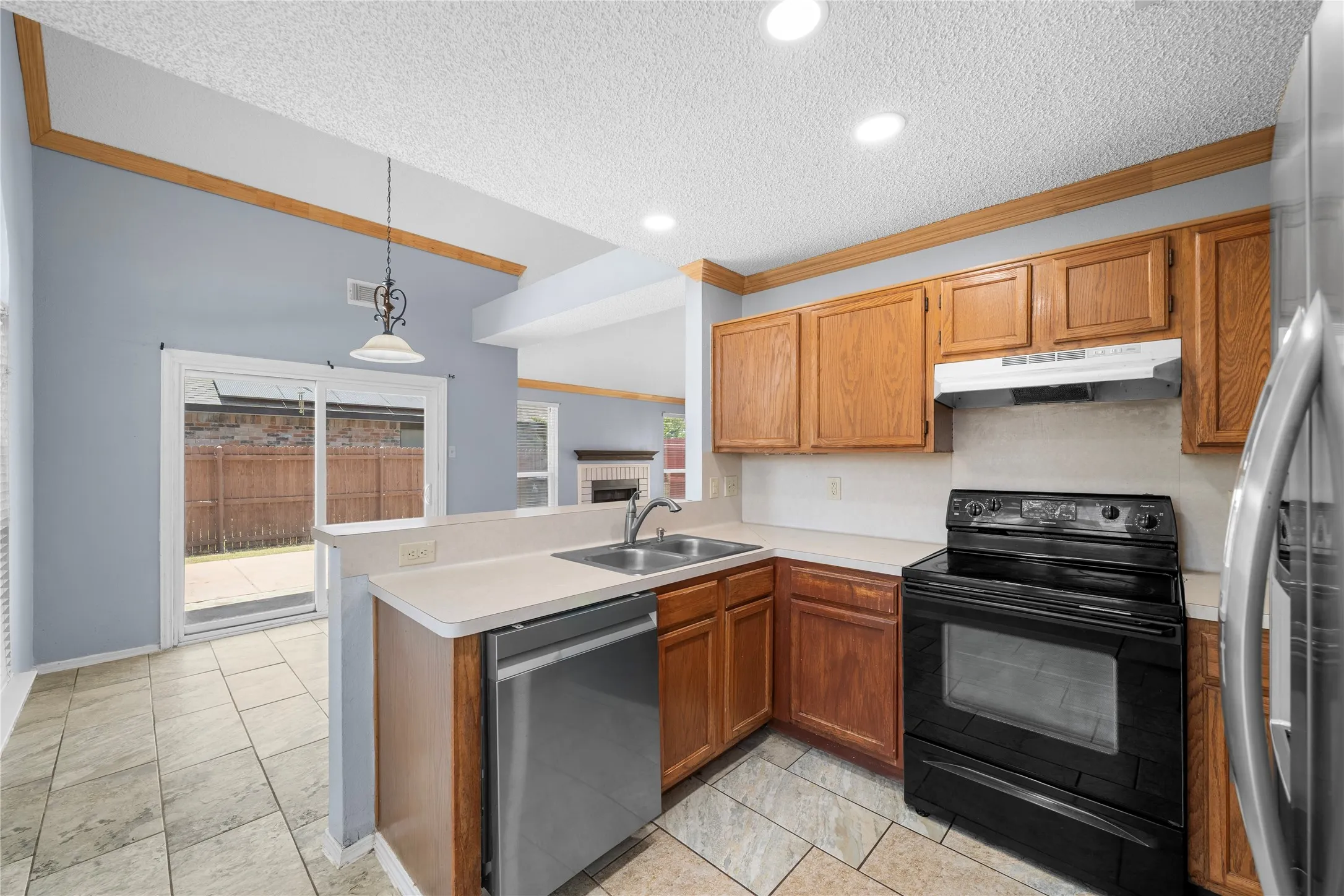 Kitchen featuring wood cabinetry, white countertops, stainless steel sink, and black electric range