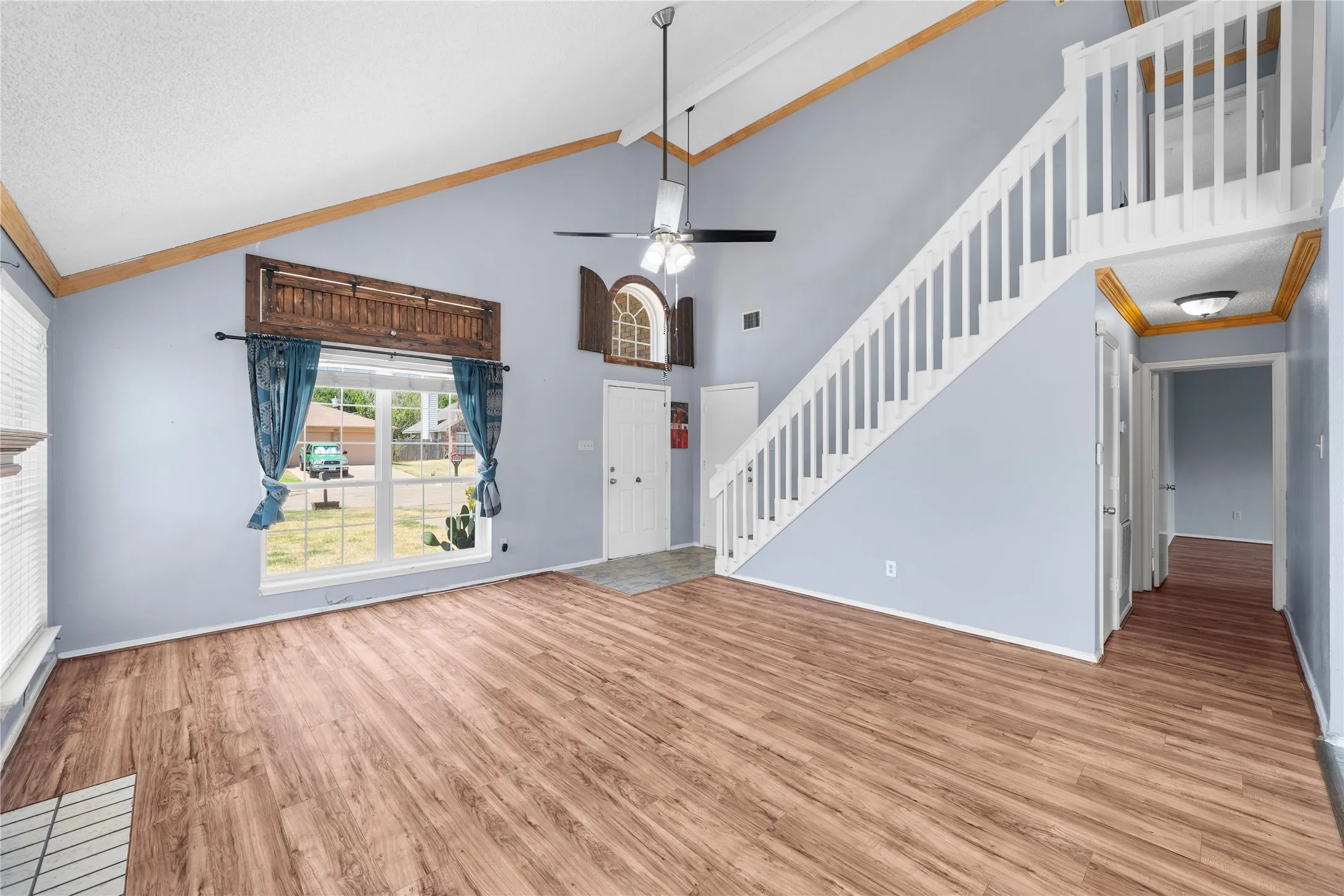 Vaulted ceiling featuring wood-finish beams, wood-finish flooring, and a white baluster staircase