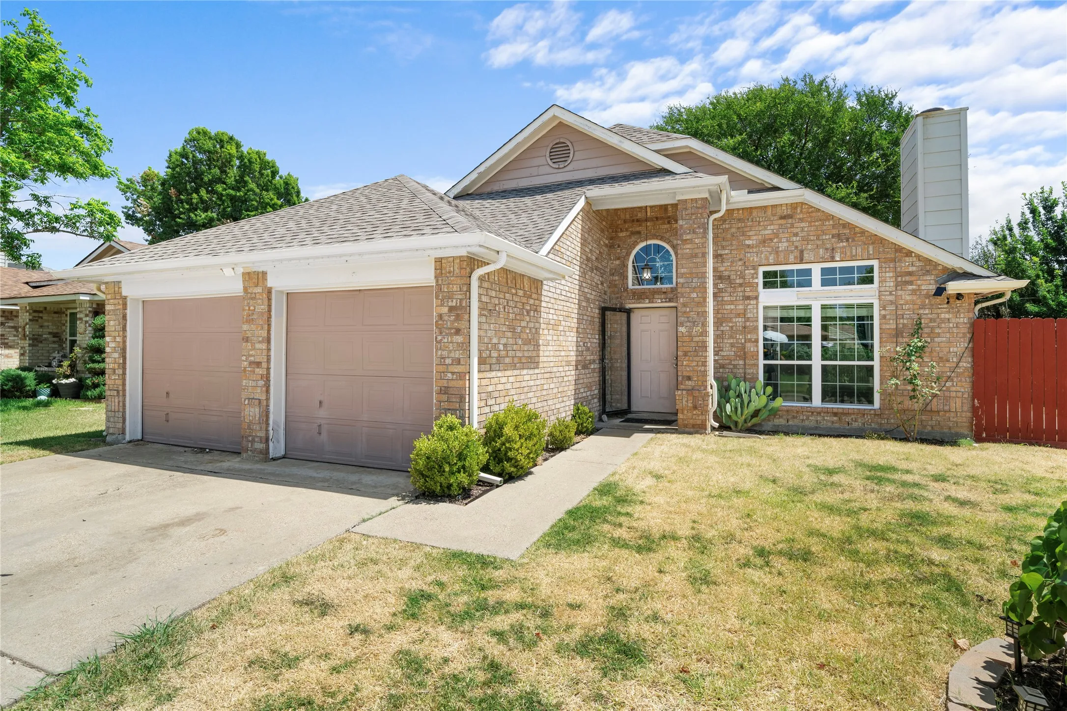 Brick exterior featuring a two-car garage, prominent front window, and an arched entry transom