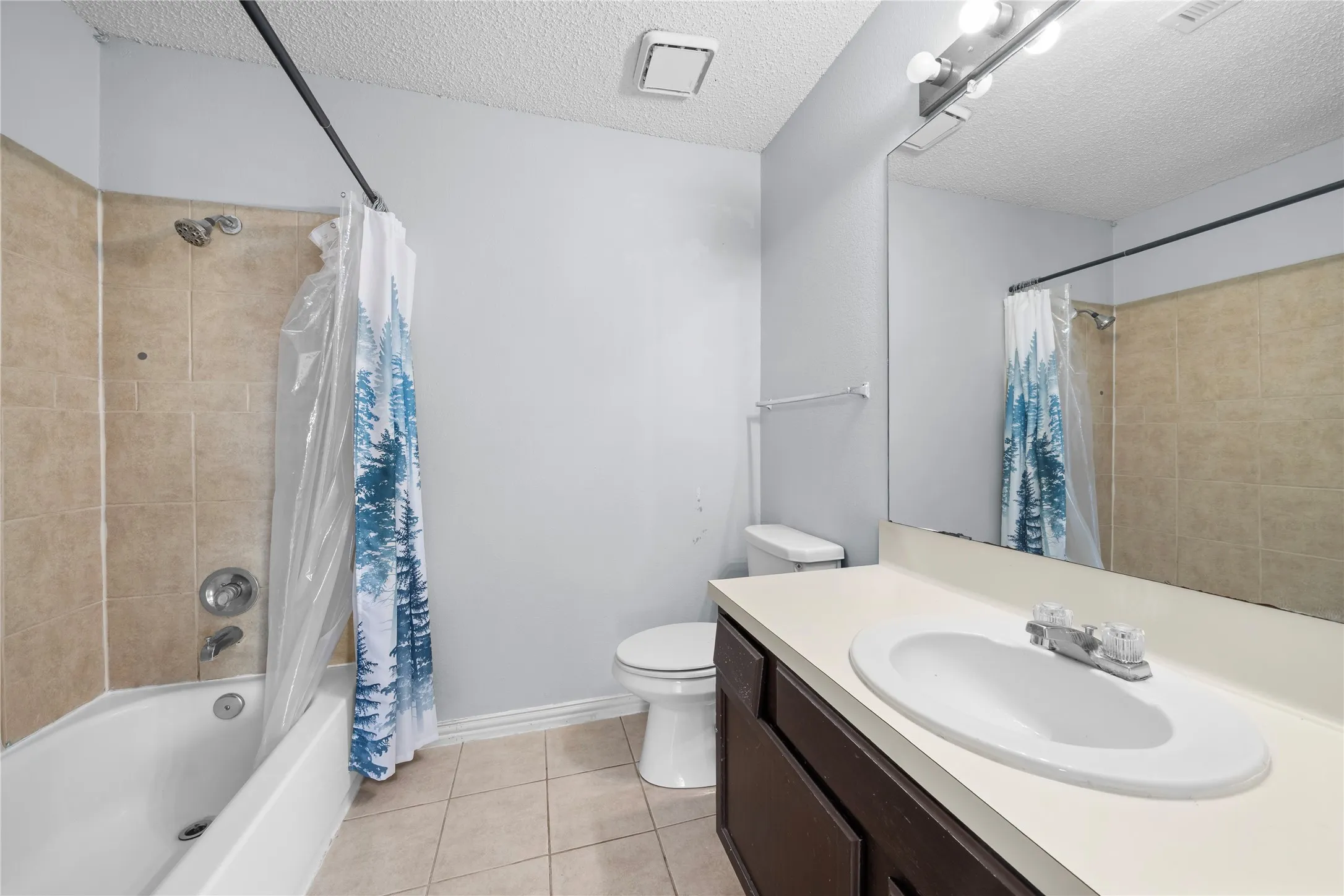 Bathroom featuring a combination shower and tub with tile surround, a single vanity with an integrated sink and light-colored countertop, and a wall-mounted mirror