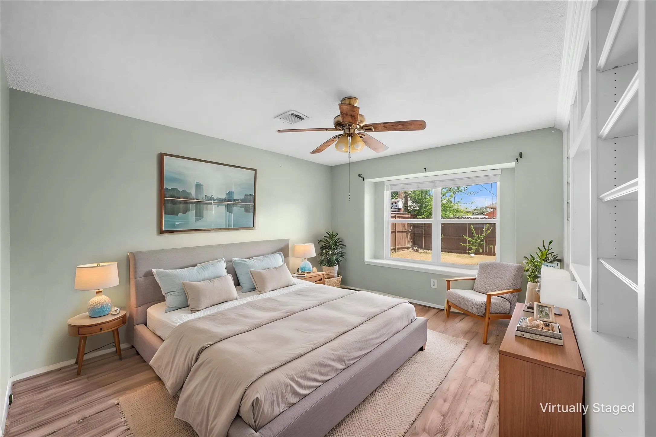 Wood-finish flooring, built-in shelving, a ceiling fan, and a large window