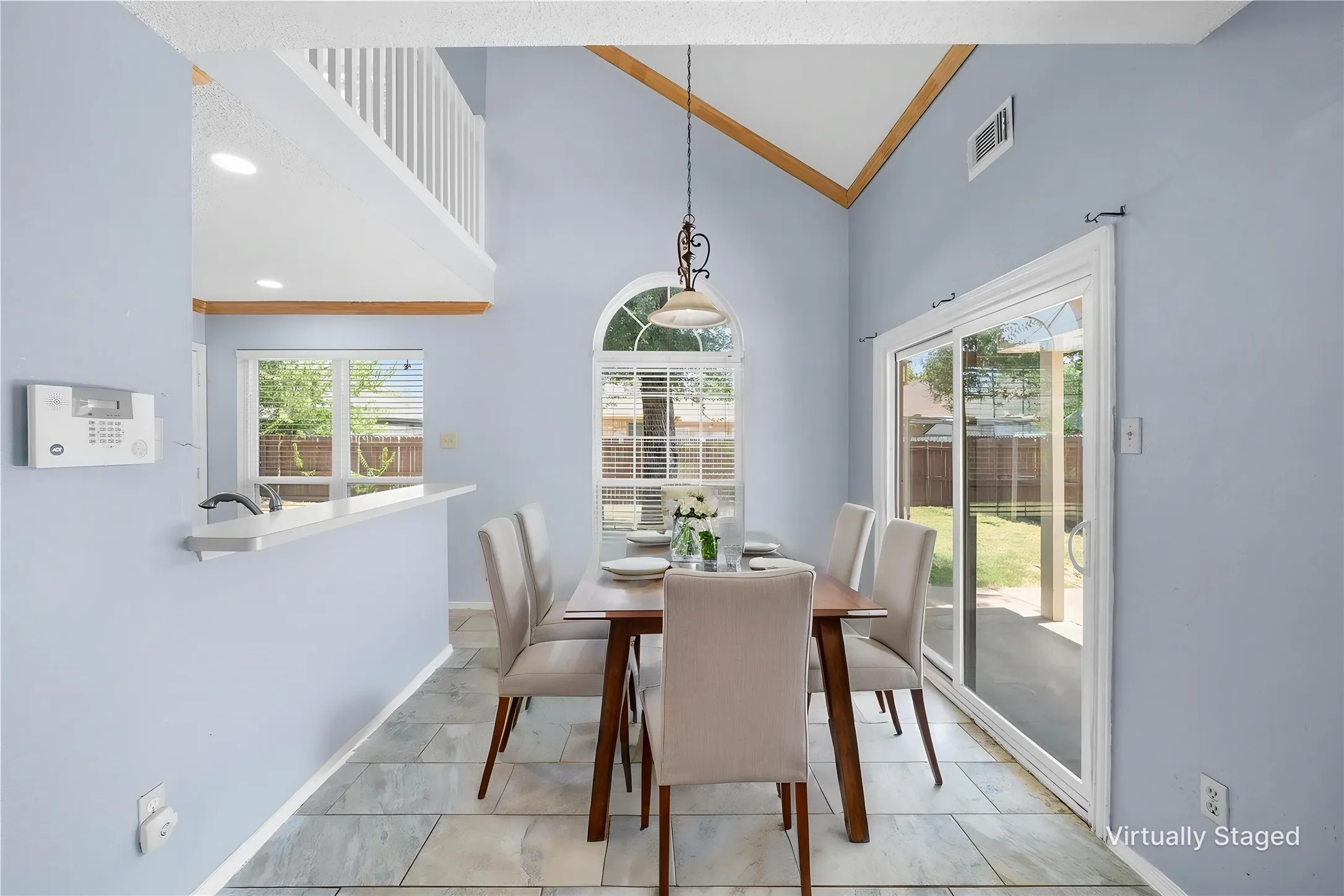 Dining area featuring a vaulted ceiling with wood-finish accents, arched window, and large sliding glass doors providing access to the exterior