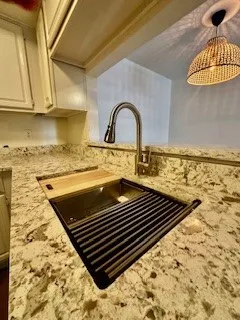 Kitchen view of light quartz countertops, stainless undermount sink with dry rack, veggie wash and cutting board -hanging light fixtures, and white cabinets