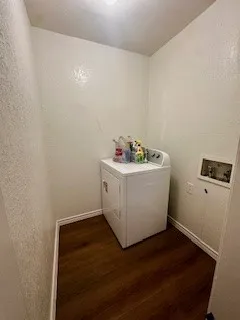 Washroom featuring wood look luxury vinyl. finished floors, washer / and  dryer, and a textured wall with built in racks (not shown)
